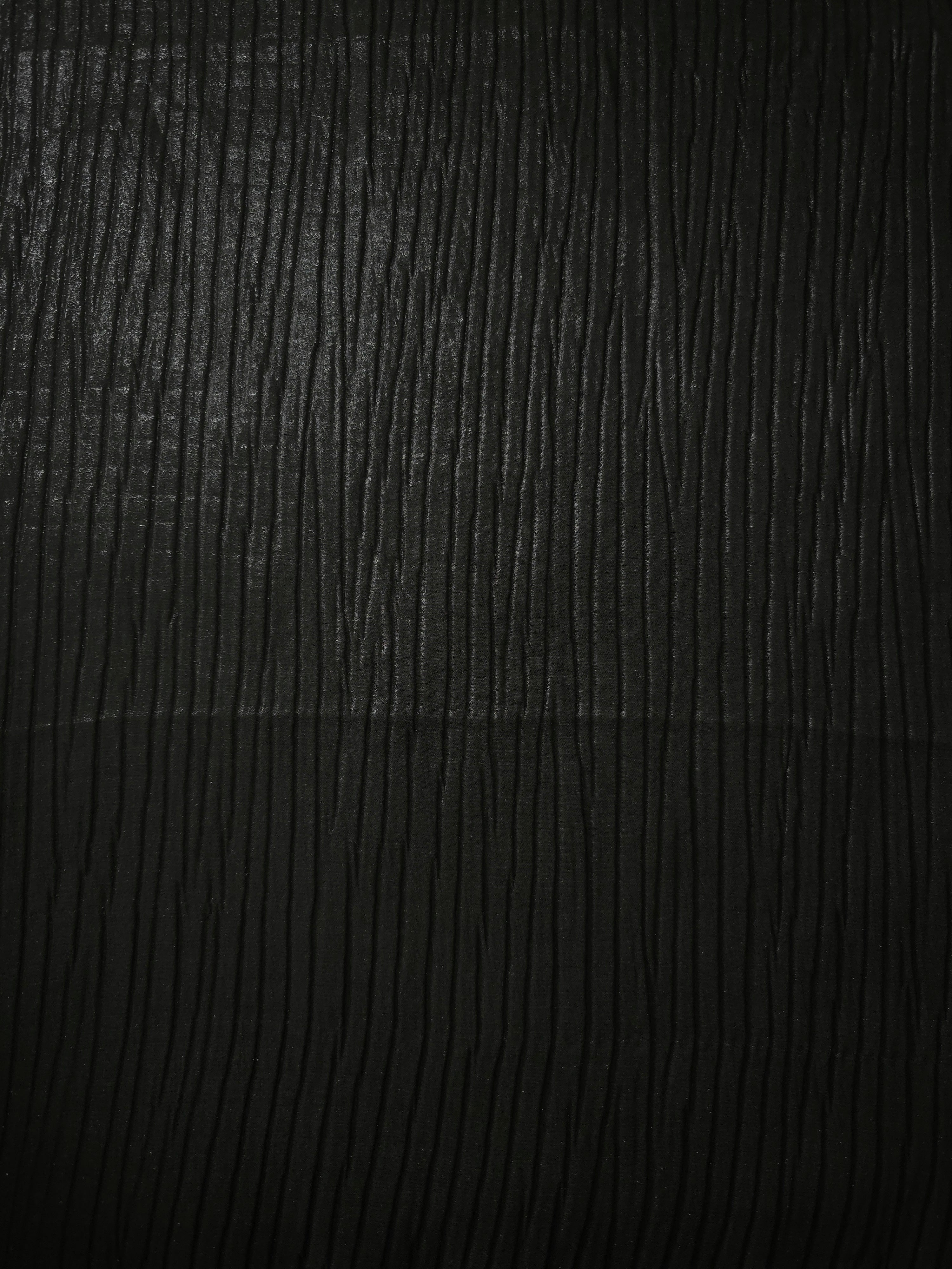 Surface detail of Jet Black classic plissé shimmer fabric showcases regular pleated texture for evening clutches, garment accents and special-occasion pieces.