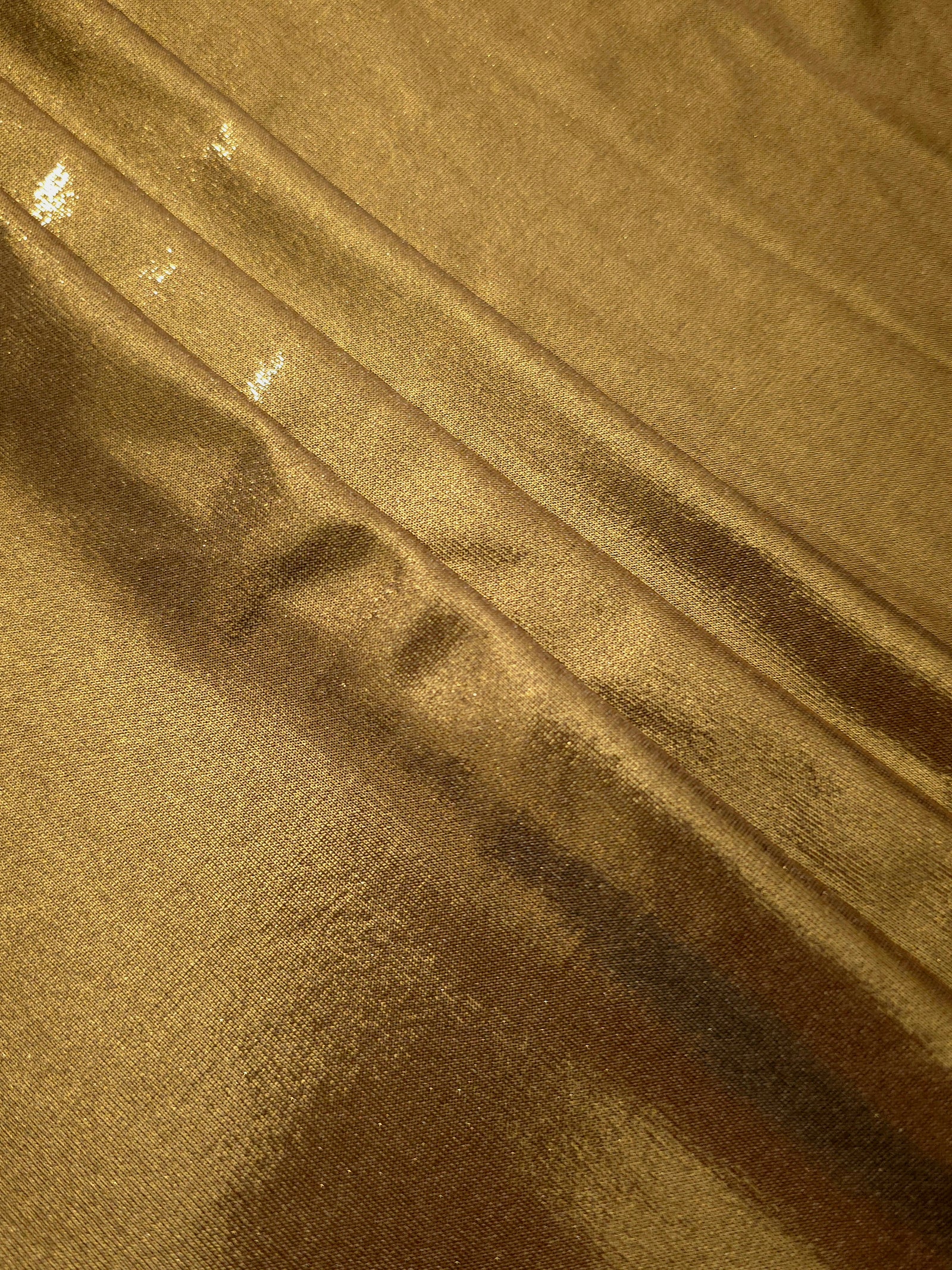 Antique Bronze shimmer spandex fabric stacked in soft layers, revealing metallic reflection for costumes, dresses and creative apparel