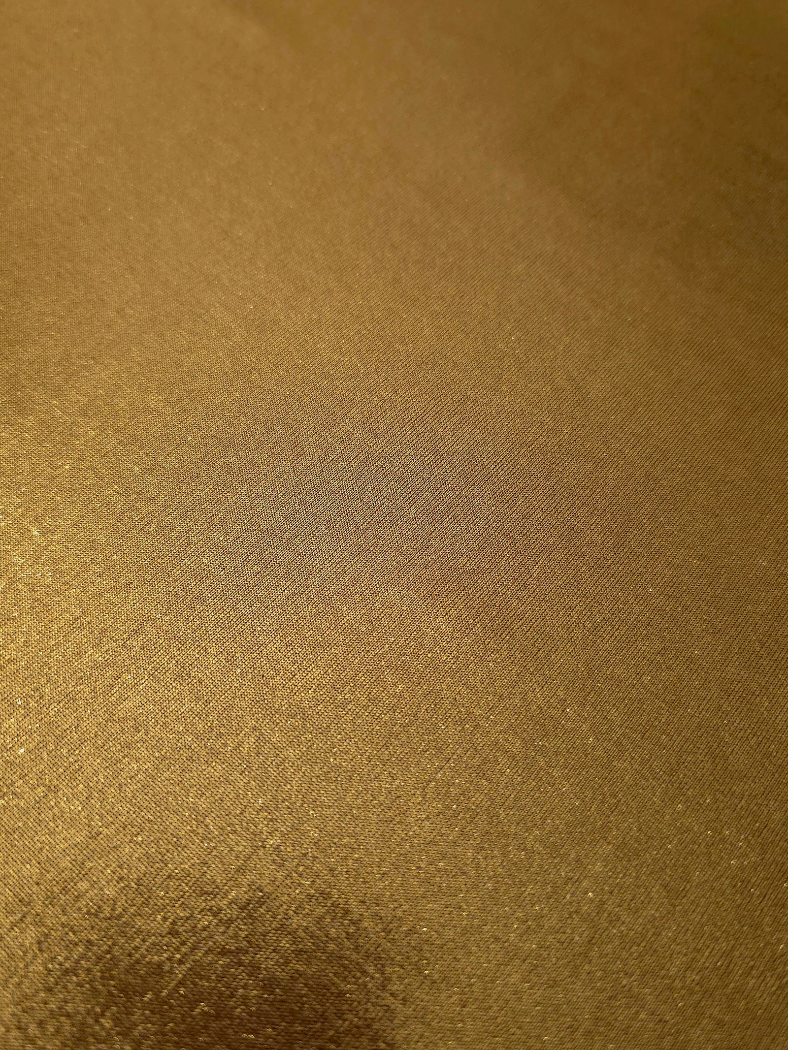 Gently folded Antique Bronze shimmer spandex fabric showing luminous foil finish for tops, skirts and occasion garments