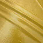 Antique Gold metallic foiled spandex in layered folds, highlighting reflective texture and flexible structure for stage and eveningwear
