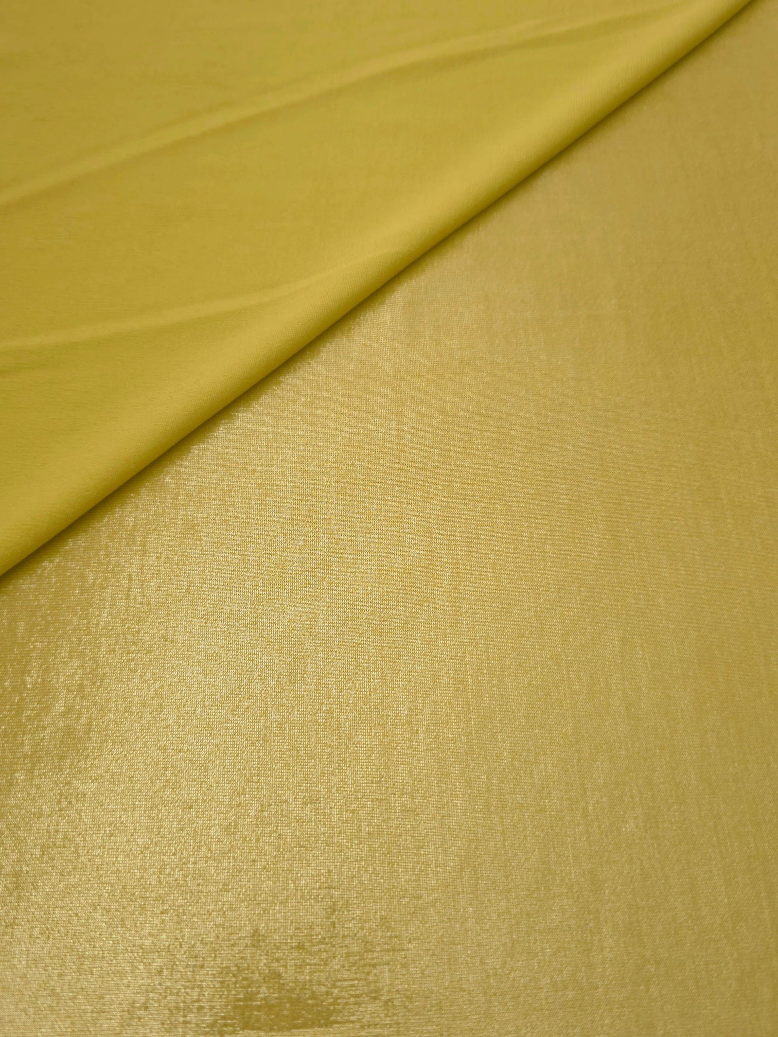 Soft fold of Antique Gold metallic foiled spandex highlighting reflective sheen and supple movement for dresses and stagewear