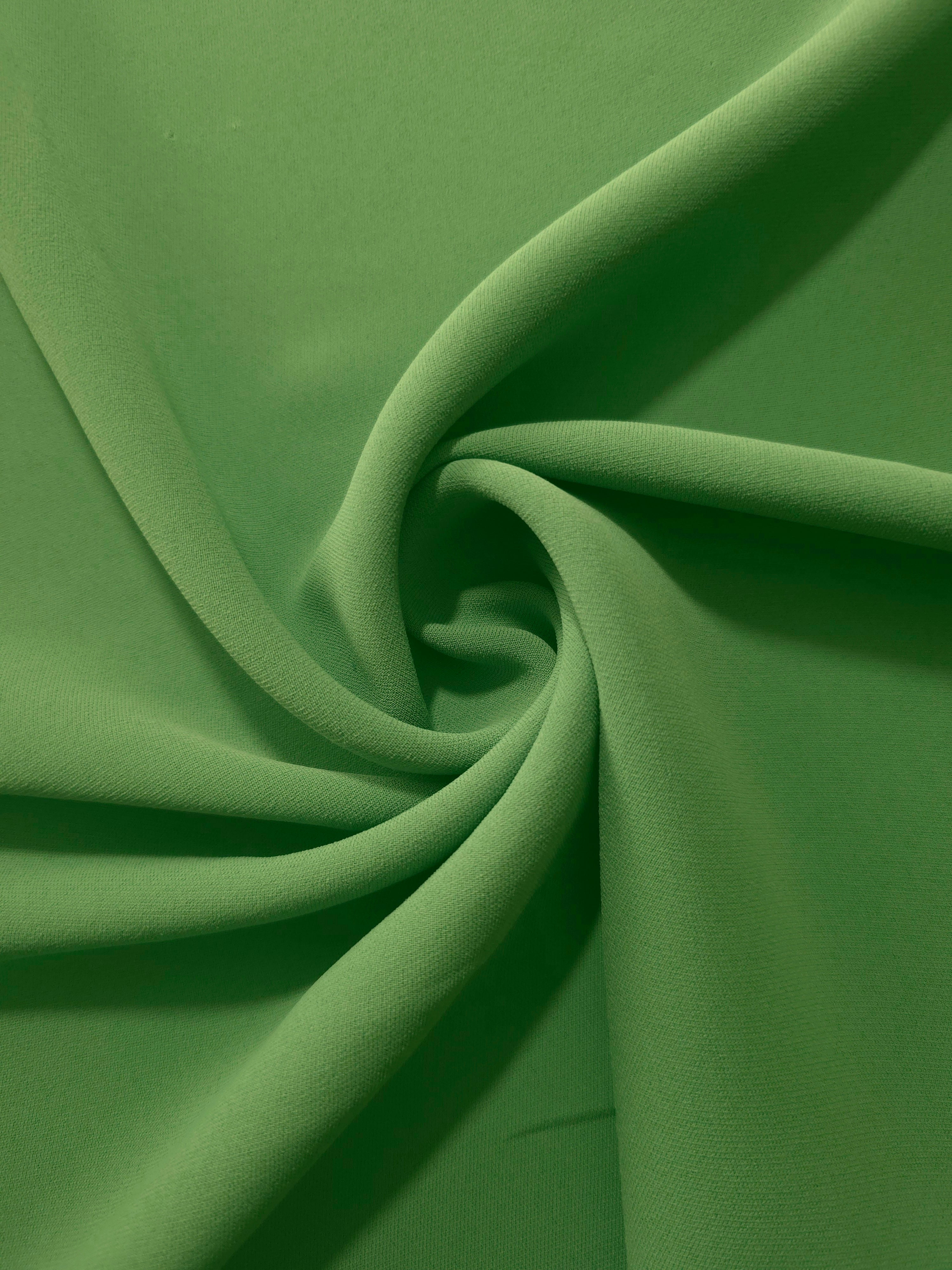 Avocado Green polyester crepe in a spiral drape, showing flowing form for dresses and modest garments