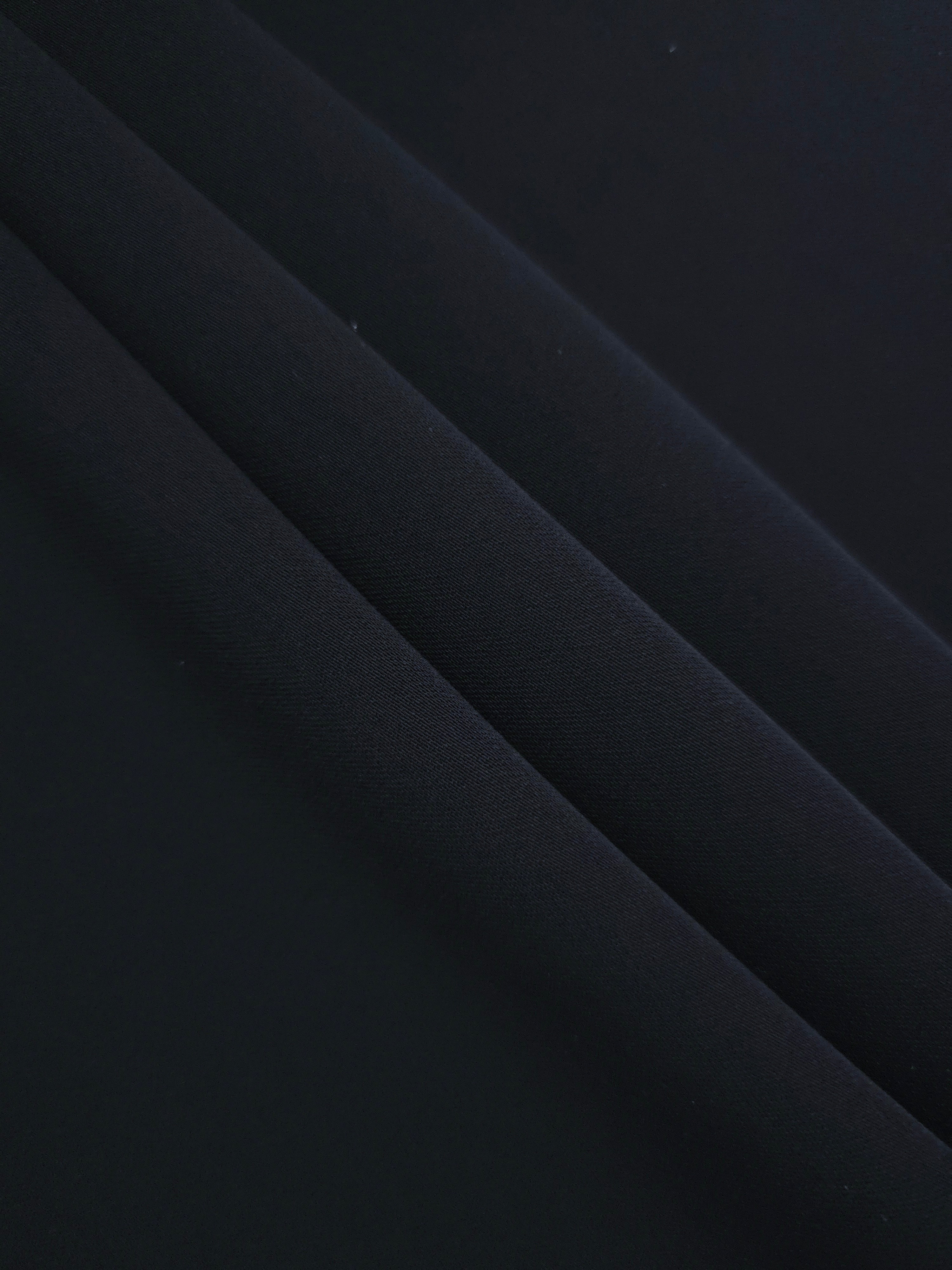 Blue Black mechanical polyester crepe in layered folds, showing gentle stretch and structure for dressmaking