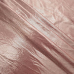 Blush Champagne metallic foiled spandex in layered folds, highlighting reflective texture and flexible structure for stage and eveningwear
