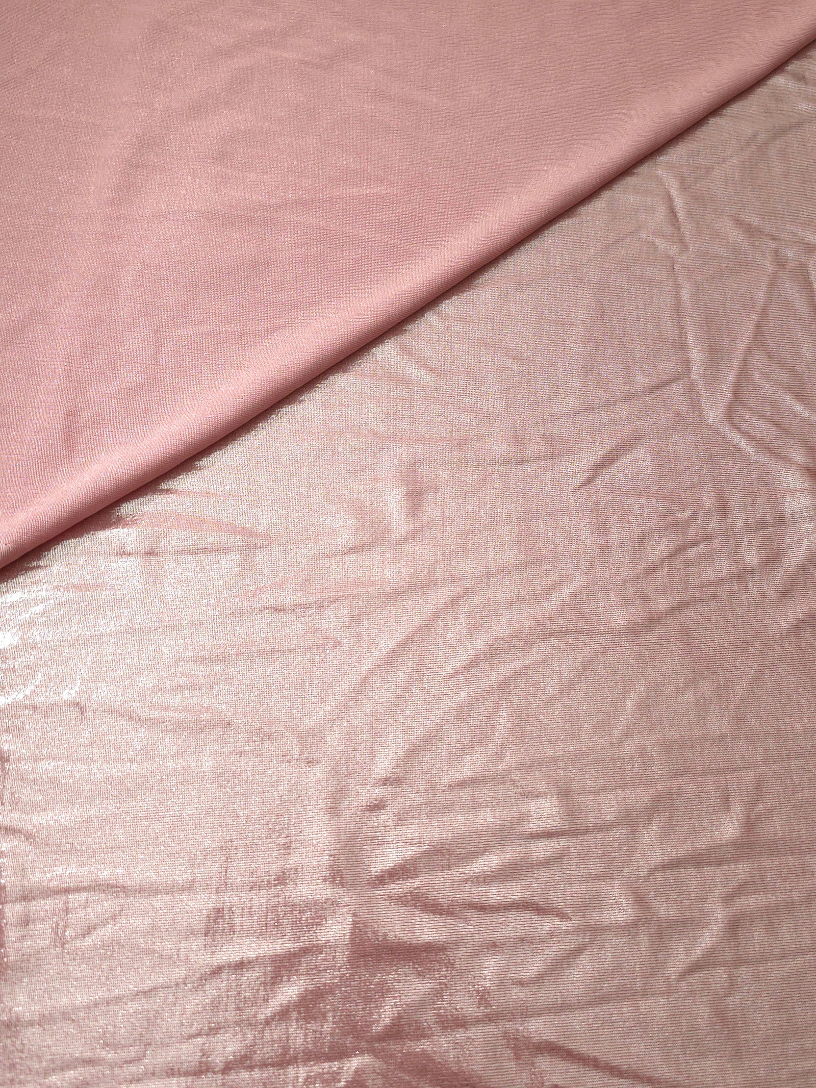 Soft fold of Blush Champagne metallic foiled spandex highlighting reflective sheen and supple movement for dresses and stagewear
