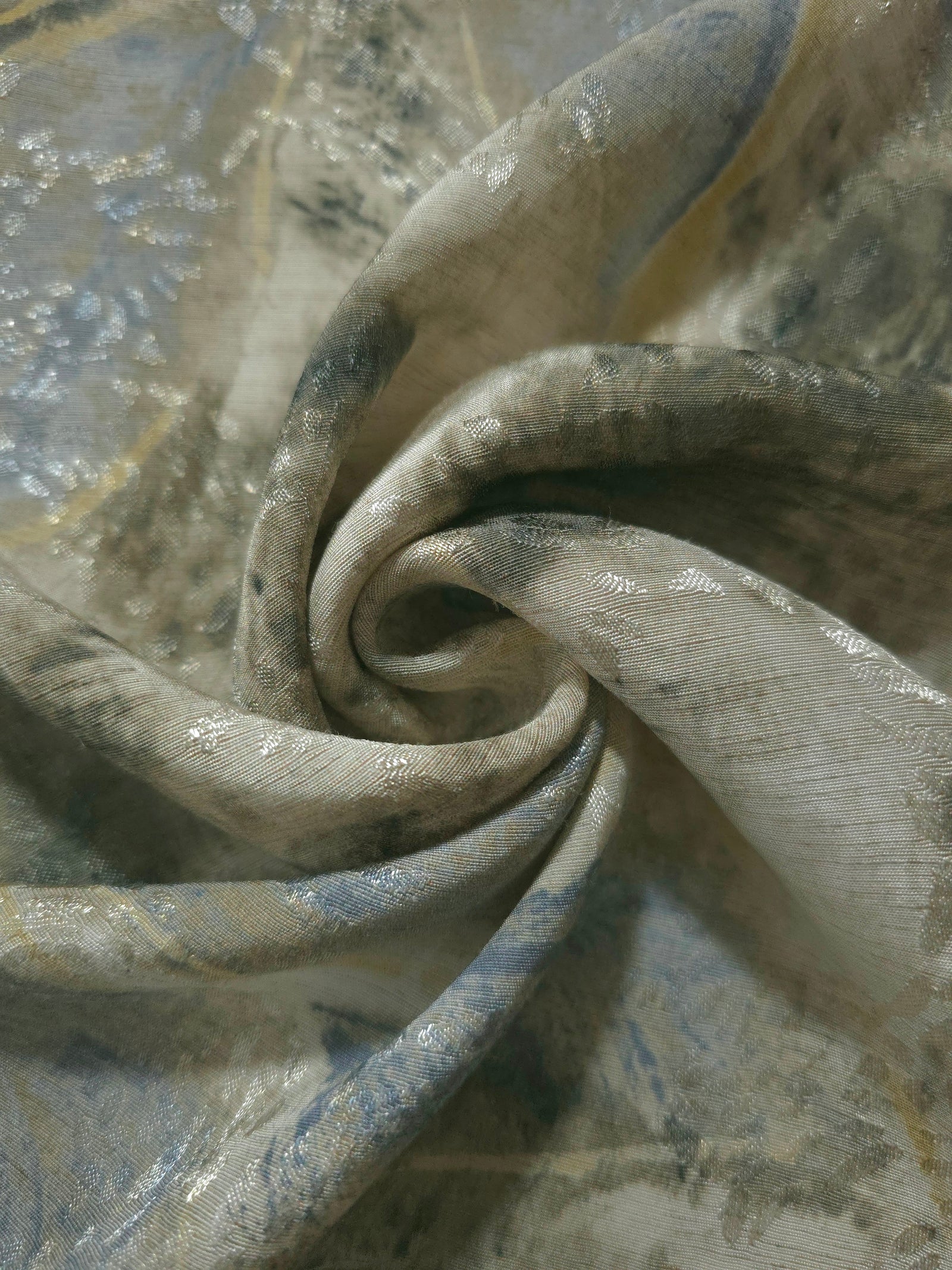 Blue botanical shadow jacquard fabric folded to show linen-like texture, body and apparel drape.