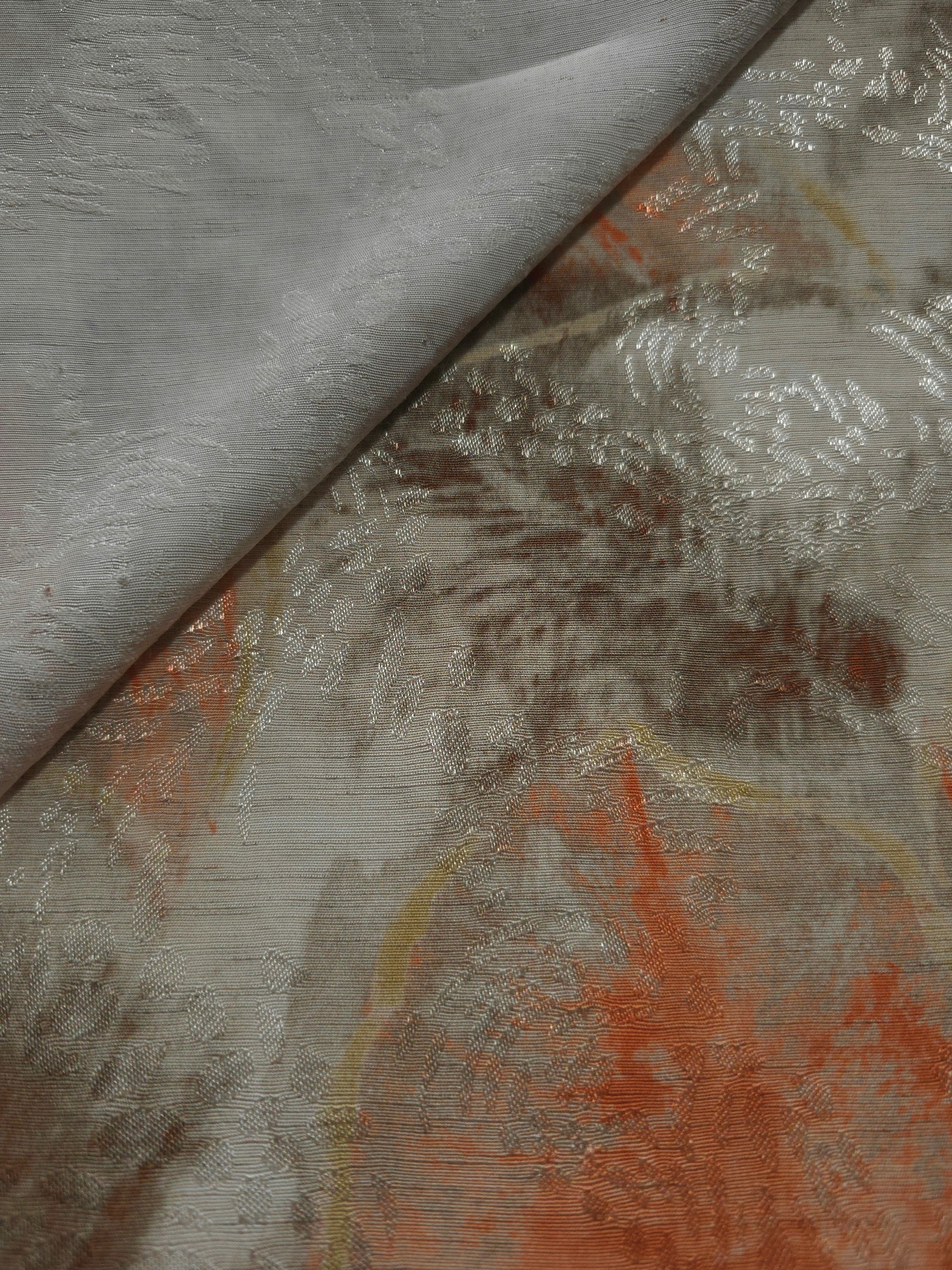 Orange botanical shadow linen-look jacquard fabric close-up showing raised woven texture and leaf motif.