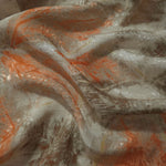 Orange botanical shadow jacquard fabric draped to show soft structure, movement and linen-like surface.