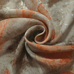 Orange botanical shadow linen-look jacquard fabric folded to show body, texture and pattern depth.