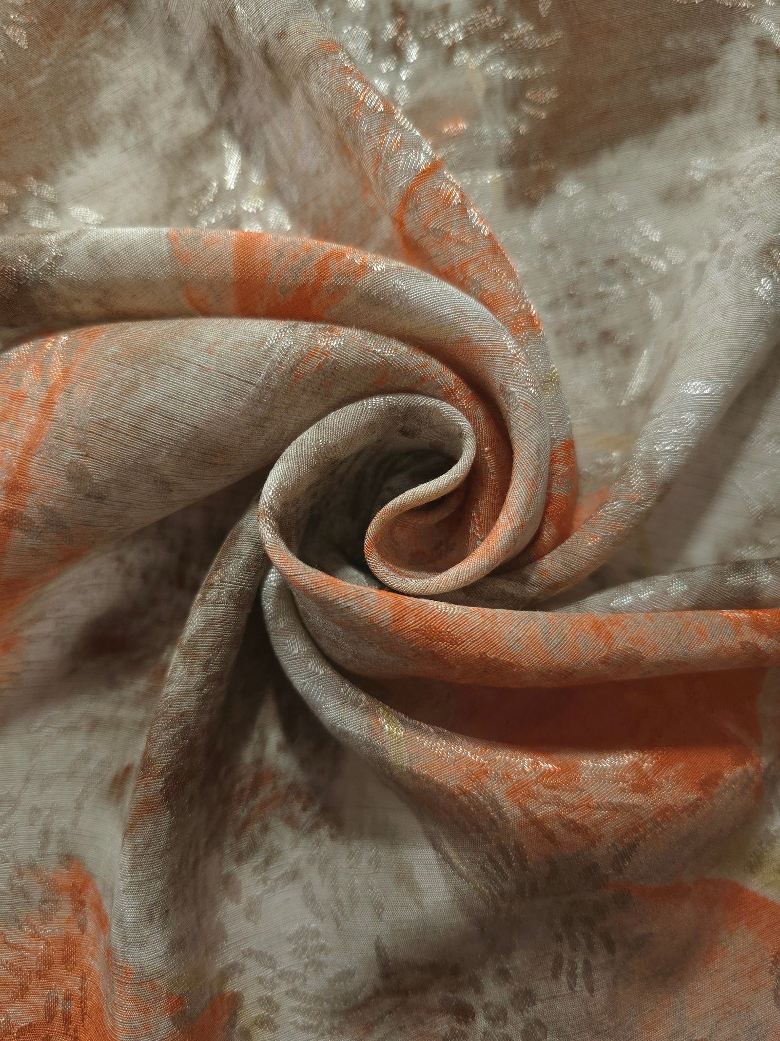 Orange botanical shadow linen-look jacquard fabric folded to show body, texture and pattern depth.