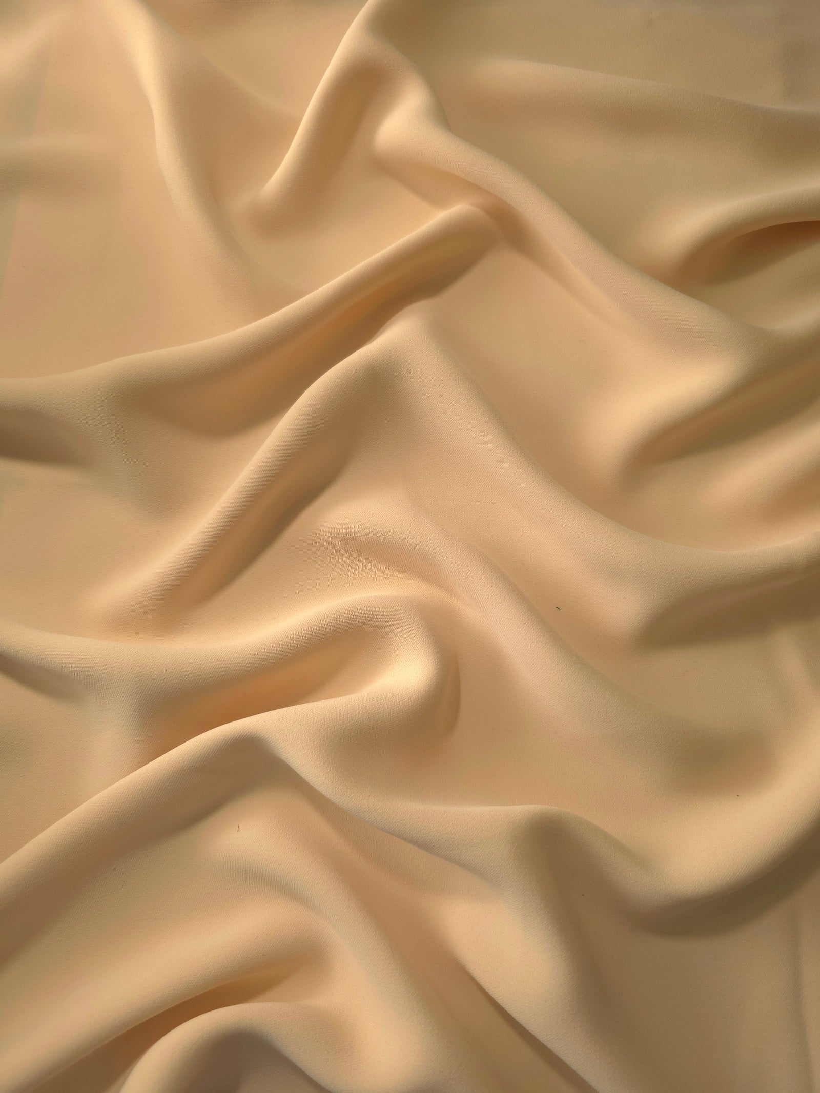 Camel Beige polyester crepe in long draped folds, showing flowing coverage for abayas and modest fashion