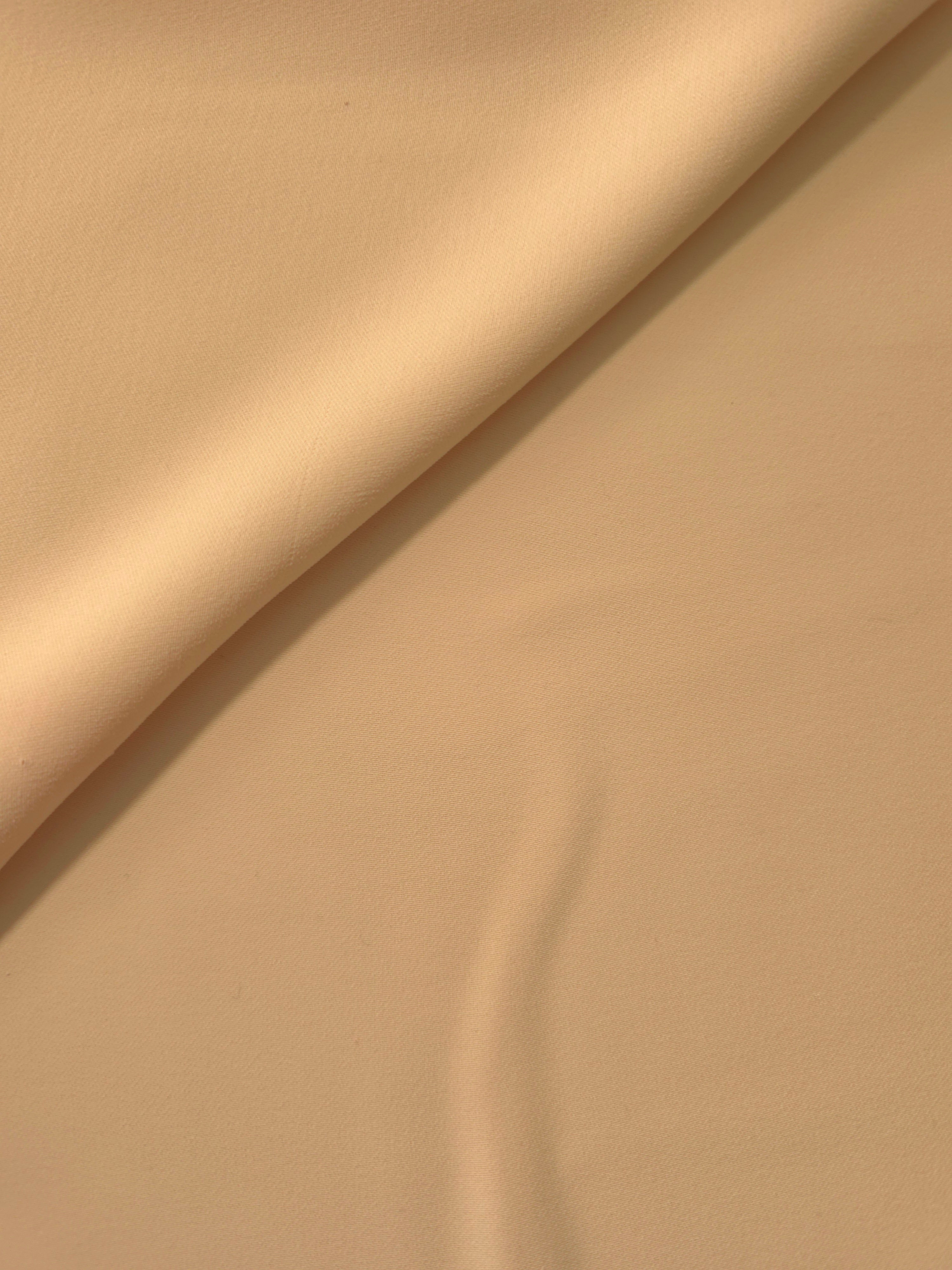 Soft fold of Camel Beige opaque polyester crepe showing fluid dressmaking drape for dresses and skirts