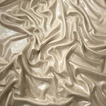 Champagne Beige metallic stretch fabric arranged in elegant folds, showing reflective movement for occasionwear, costumes and fashion design