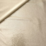 Champagne Beige metallic stretch fabric in a soft fold, revealing reflective drape for dancewear, dresses and statement apparel