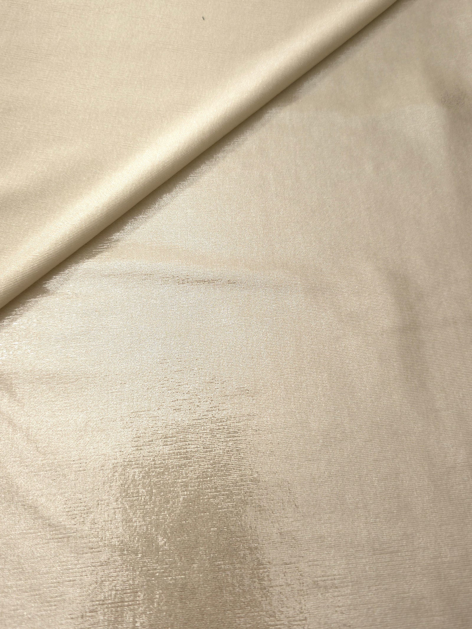 Champagne Beige metallic stretch fabric in a soft fold, revealing reflective drape for dancewear, dresses and statement apparel