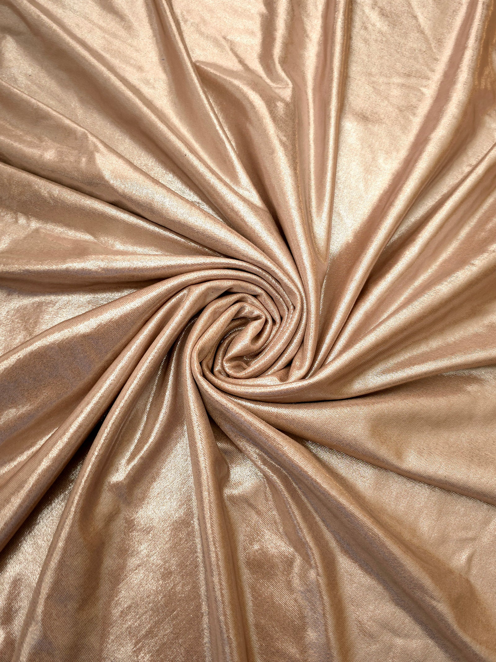 Flowing swirl of Champagne Taupe metallic stretch fabric, showing dynamic foil reflection for stagewear, skirts and creative fashion