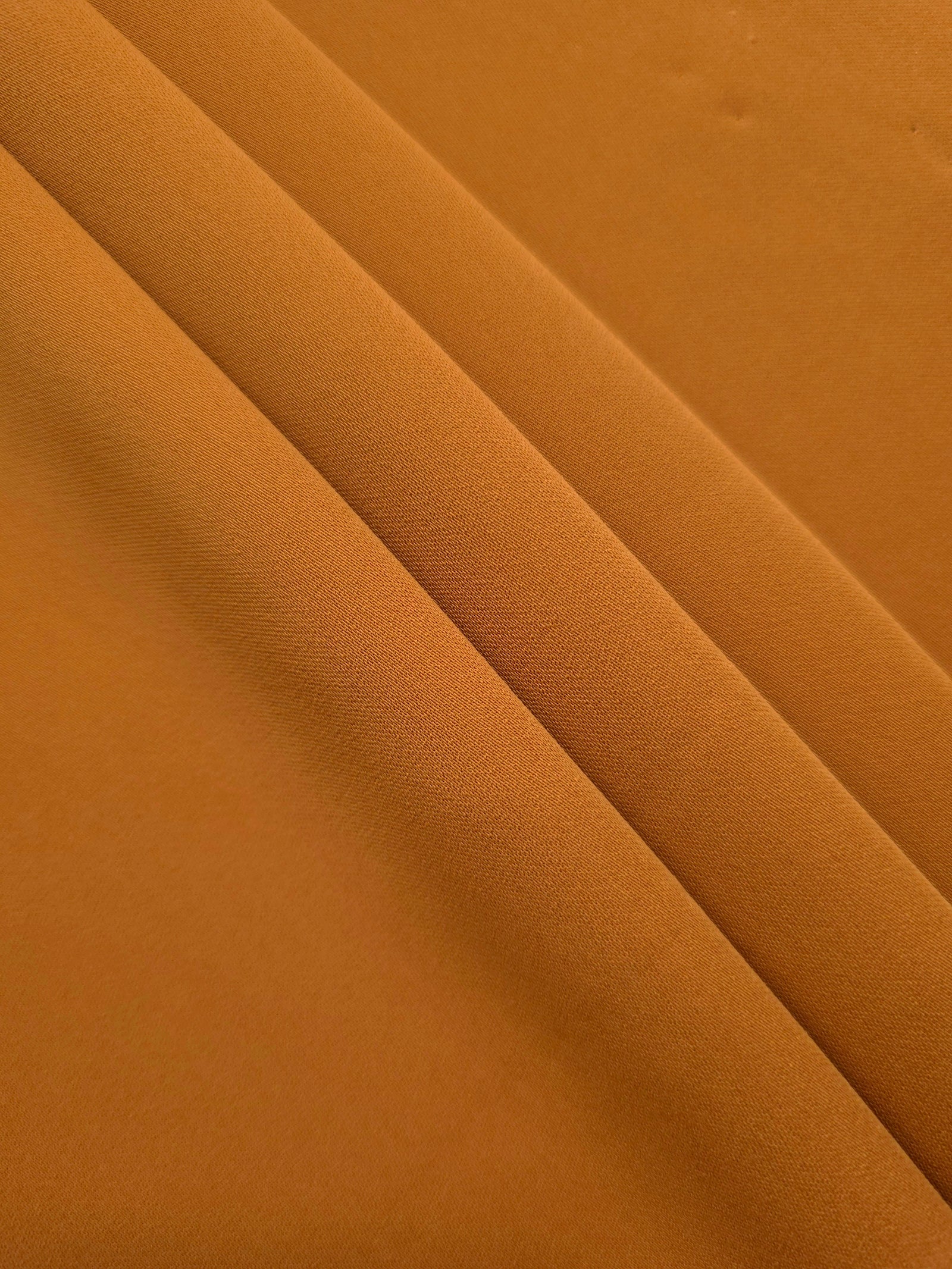 Layered Cinnamon Brown polyester crepe showing soft body and slight mechanical stretch for light tailoring
