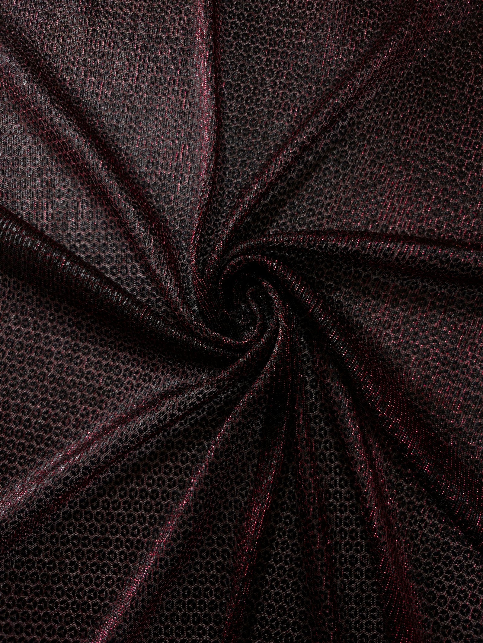 Swirl-draped Burgundy Red Sheer Circle Shimmer Stretch Tulle Fabric showing circular highlights shifting through flexible movement
