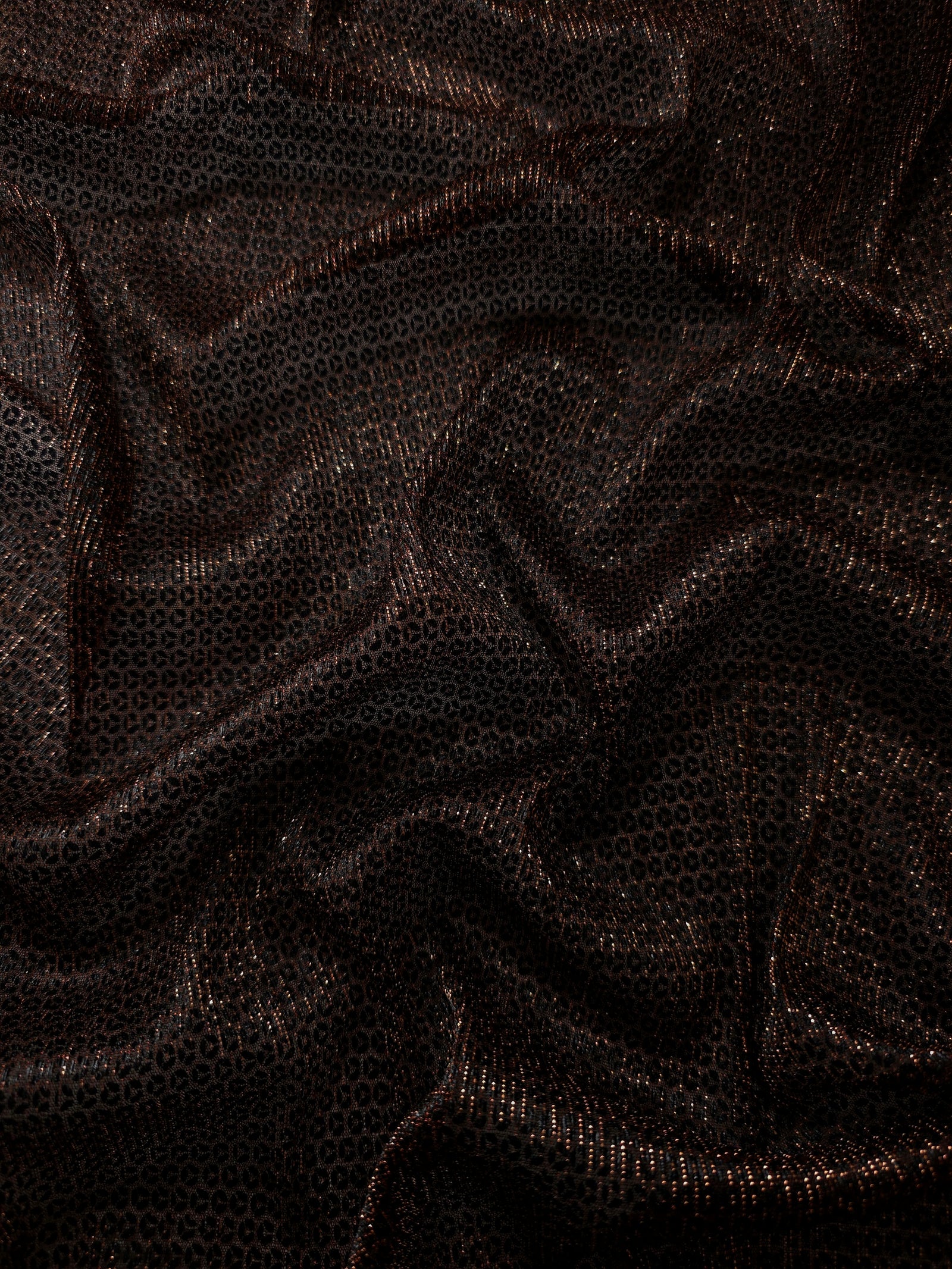 Draped Burnt Copper Sheer Circle Shimmer Stretch Tulle Fabric showing reflective round motifs across soft fluid folds