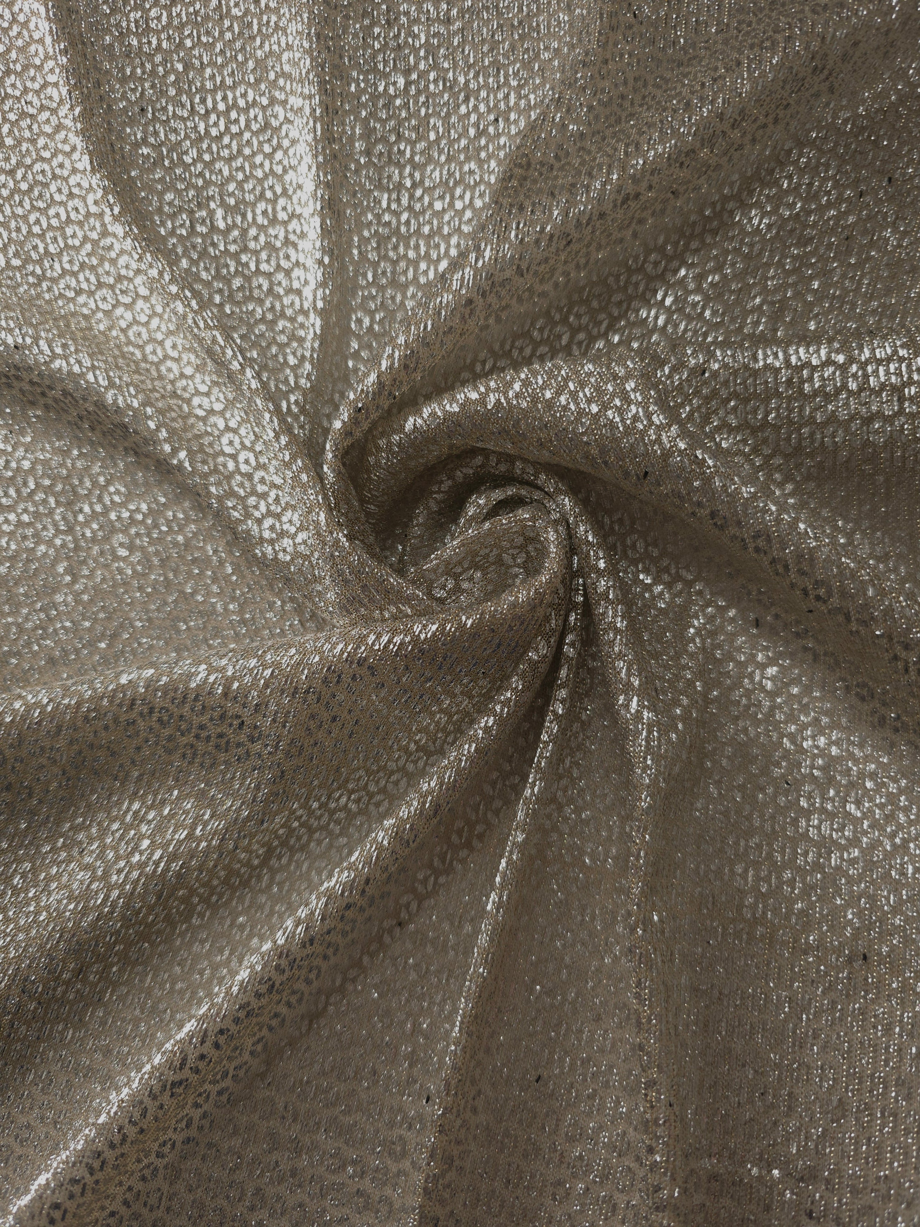 Swirl-draped Champagne Gold Sheer Circle Shimmer Stretch Tulle Fabric showing circular highlights shifting through flexible movement