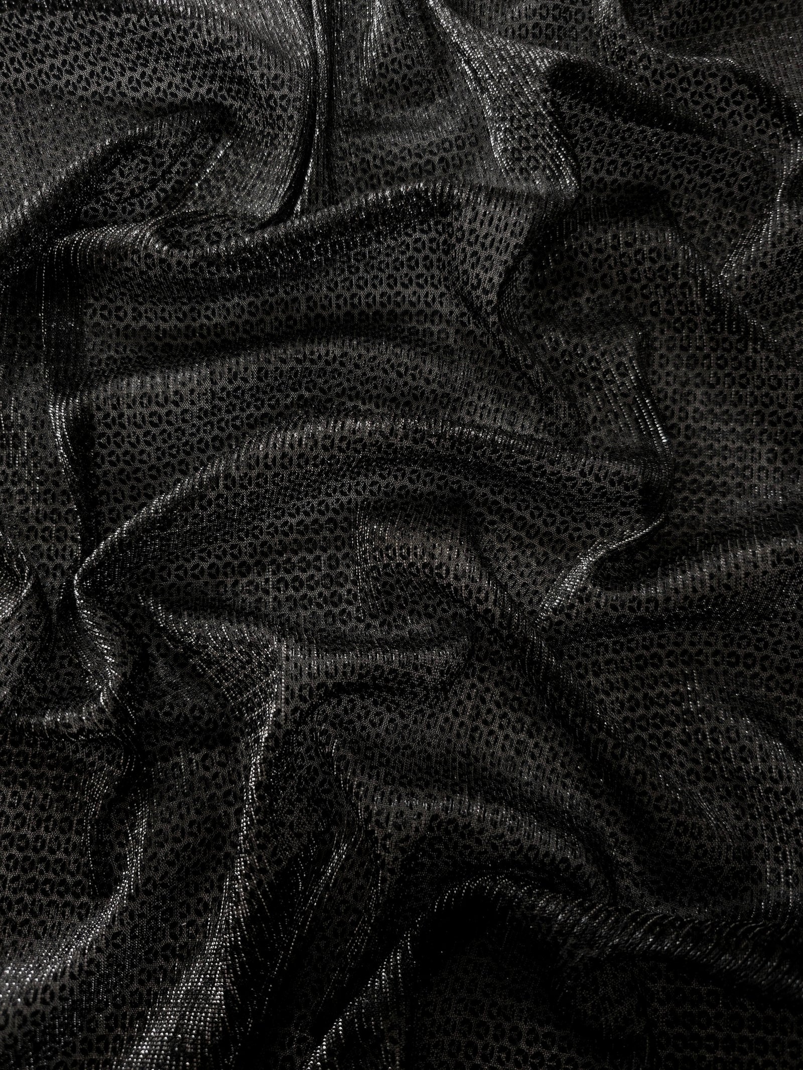 Draped Charcoal Silver Sheer Circle Shimmer Stretch Tulle Fabric showing reflective round motifs across soft fluid folds