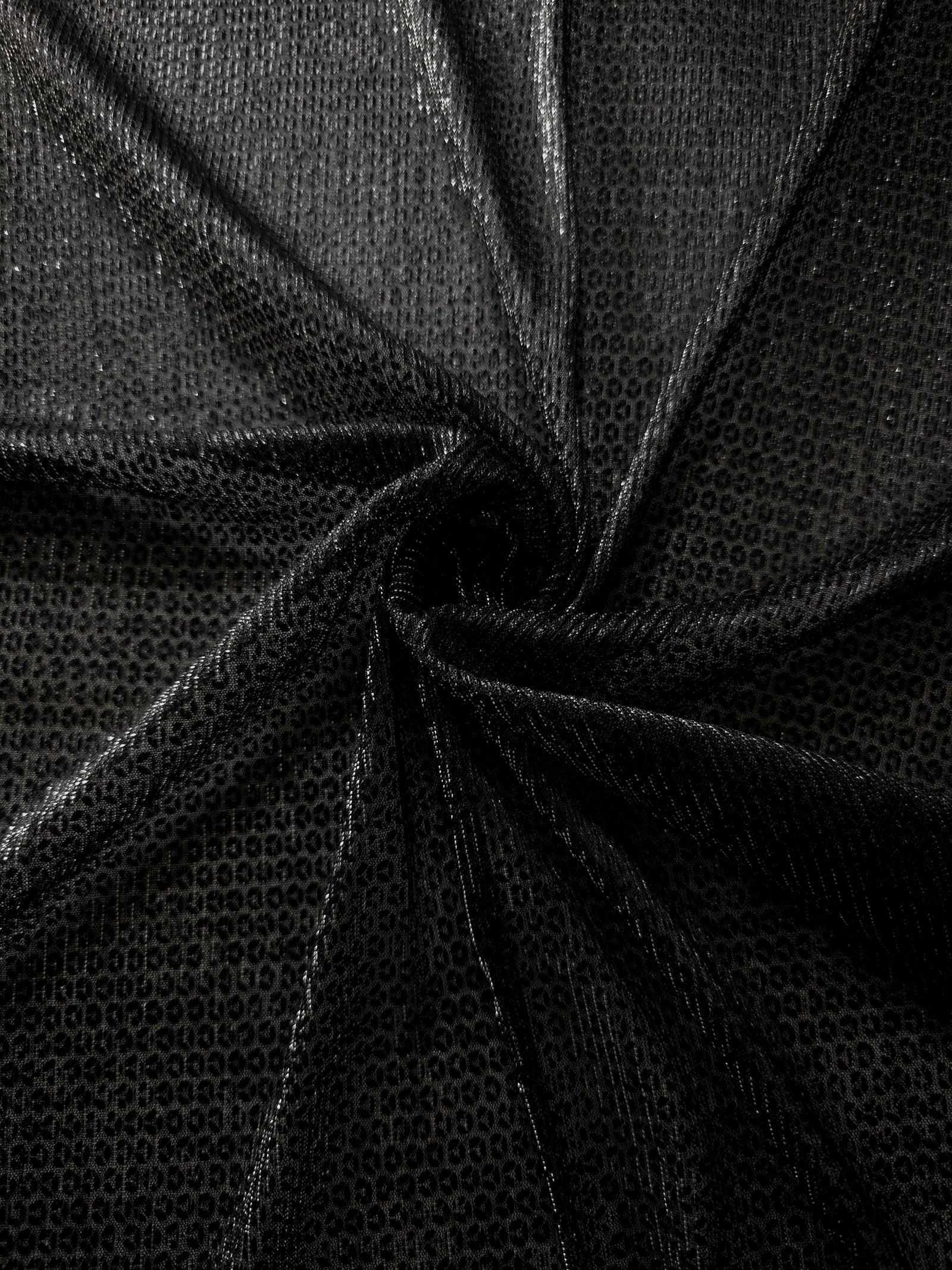 Swirl-draped Charcoal Silver Sheer Circle Shimmer Stretch Tulle Fabric showing circular highlights shifting through flexible movement