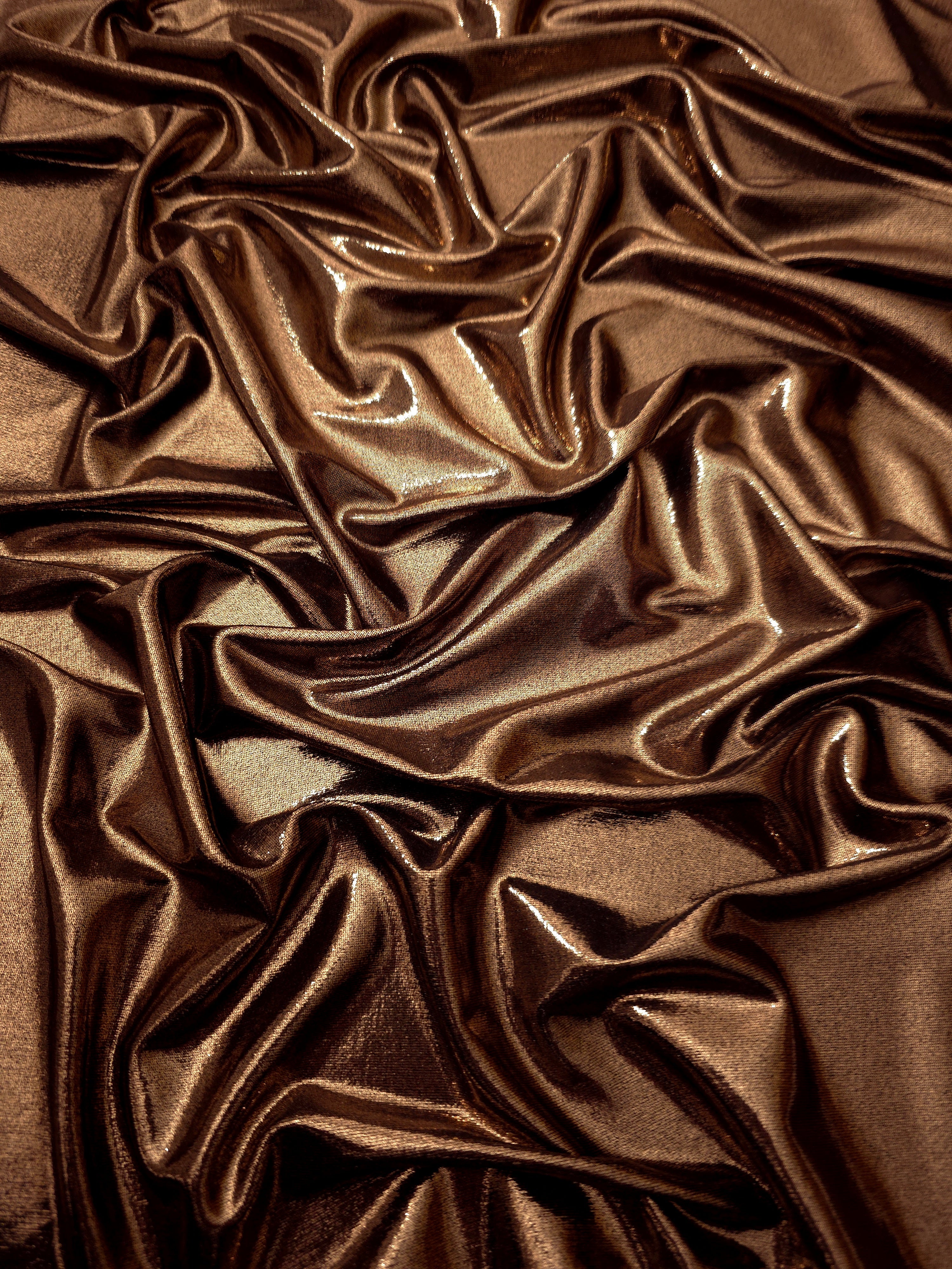 Draped Copper Brown metallic foiled spandex showing reflective folds and flexible flow for dresses, stagewear and occasion looks