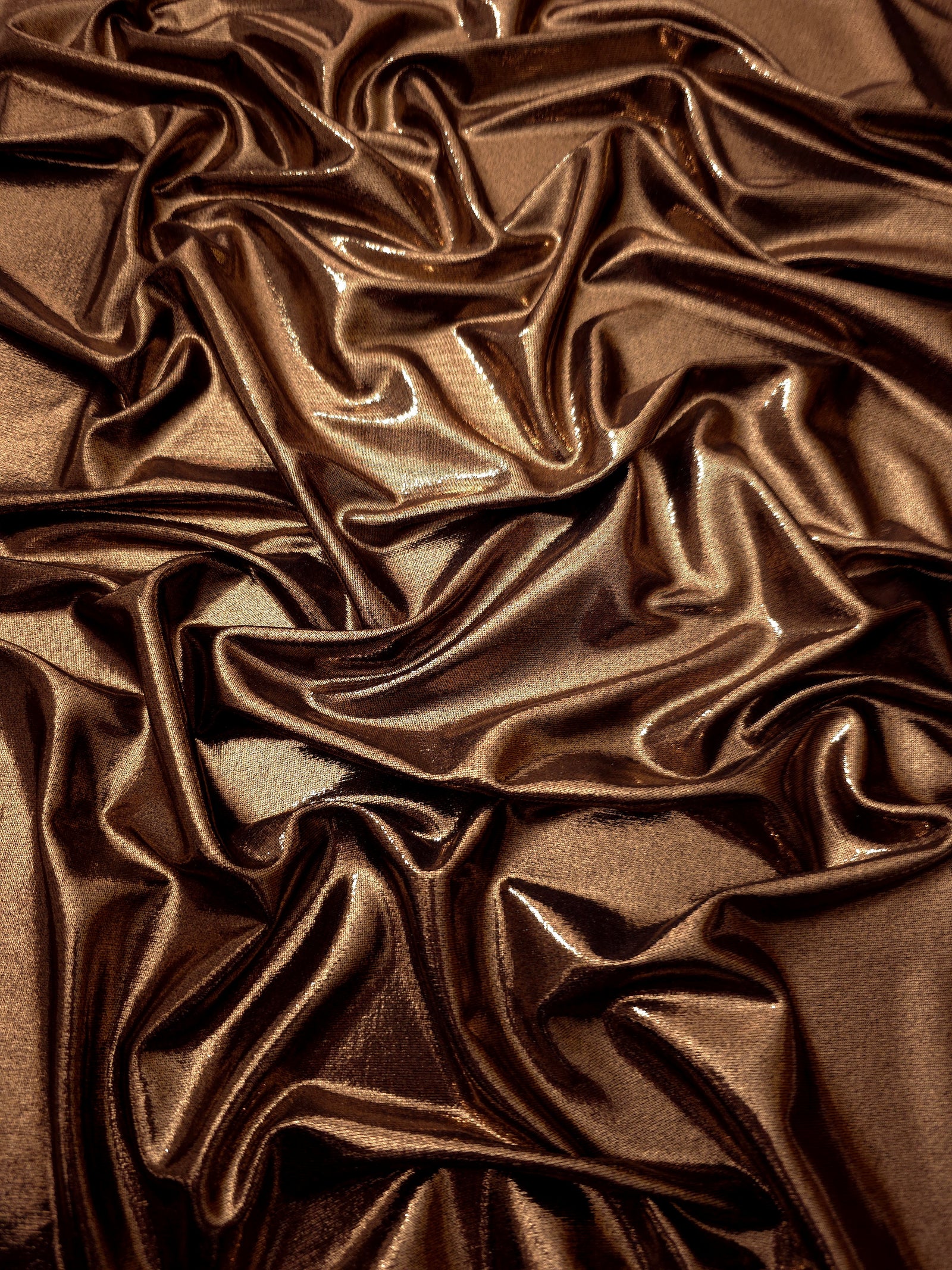 Draped Copper Brown metallic foiled spandex showing reflective folds and flexible flow for dresses, stagewear and occasion looks