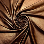 Copper Brown shimmer foiled stretch fabric arranged in a swirl, highlighting movement and reflective finish for performancewear