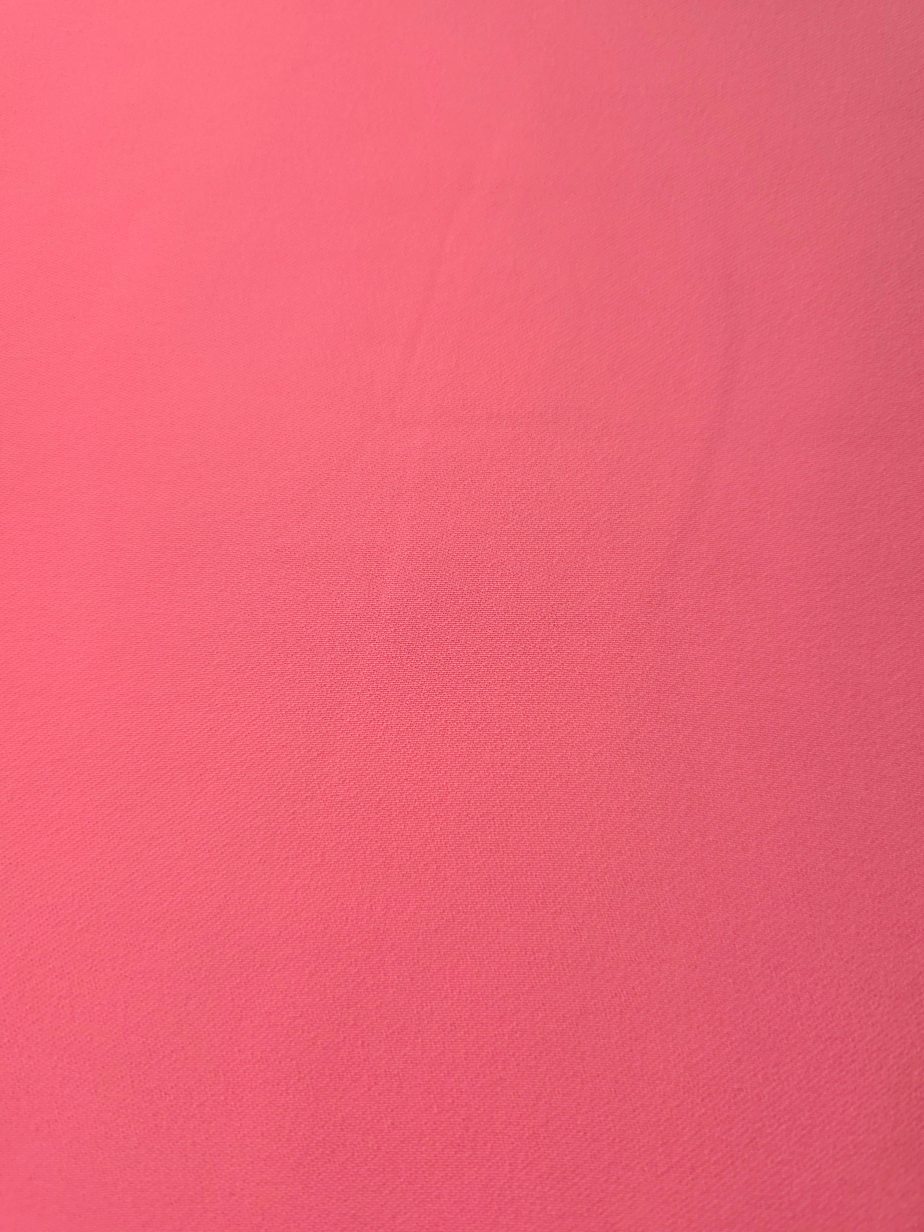 Close-up of Coral Pink mechanical polyester crepe showing fine woven texture and a smooth silky-soft hand