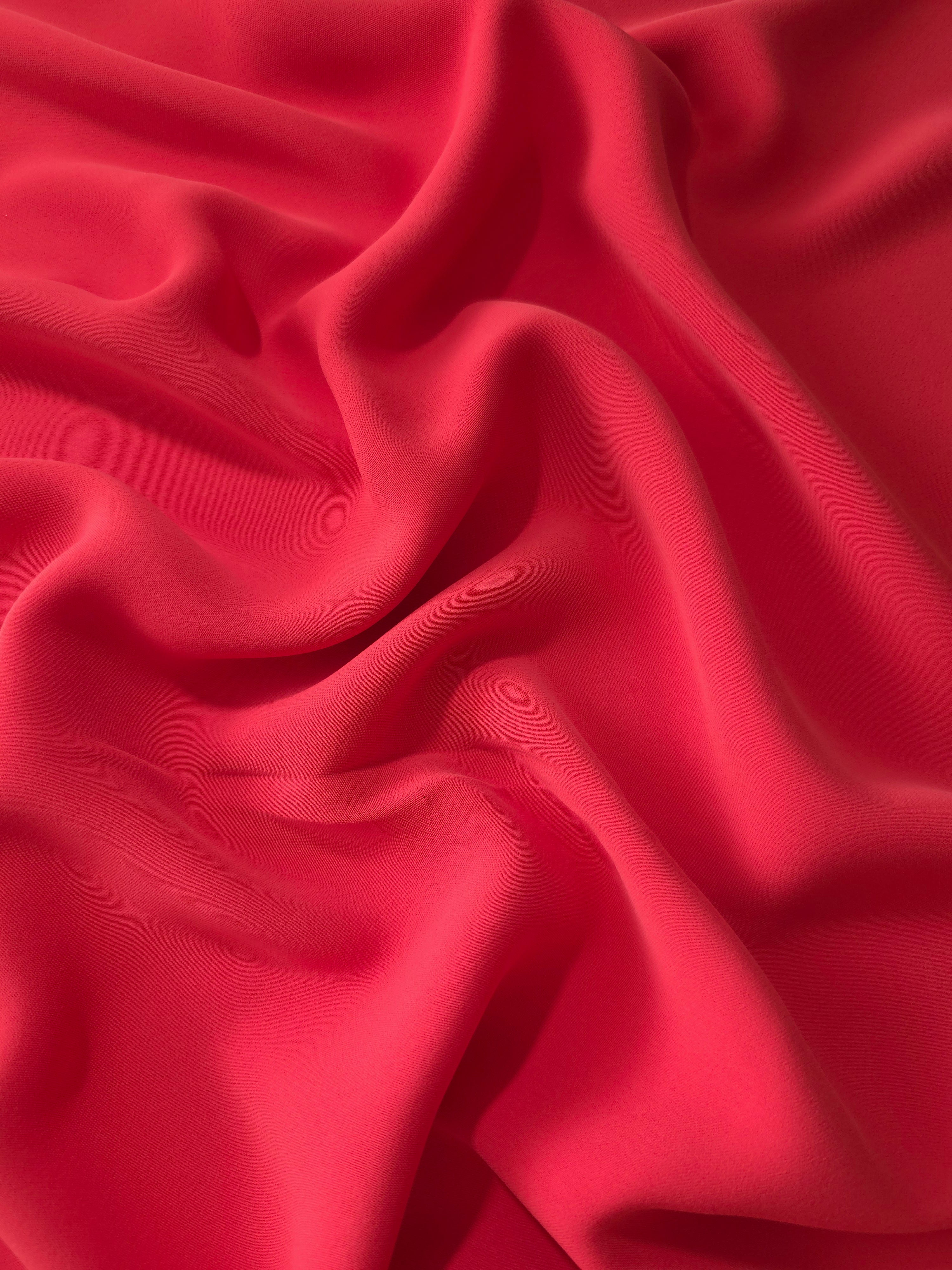 Crimson Red Italian polyester crepe shown in draped folds for occasionwear, blouses and elegant dresses