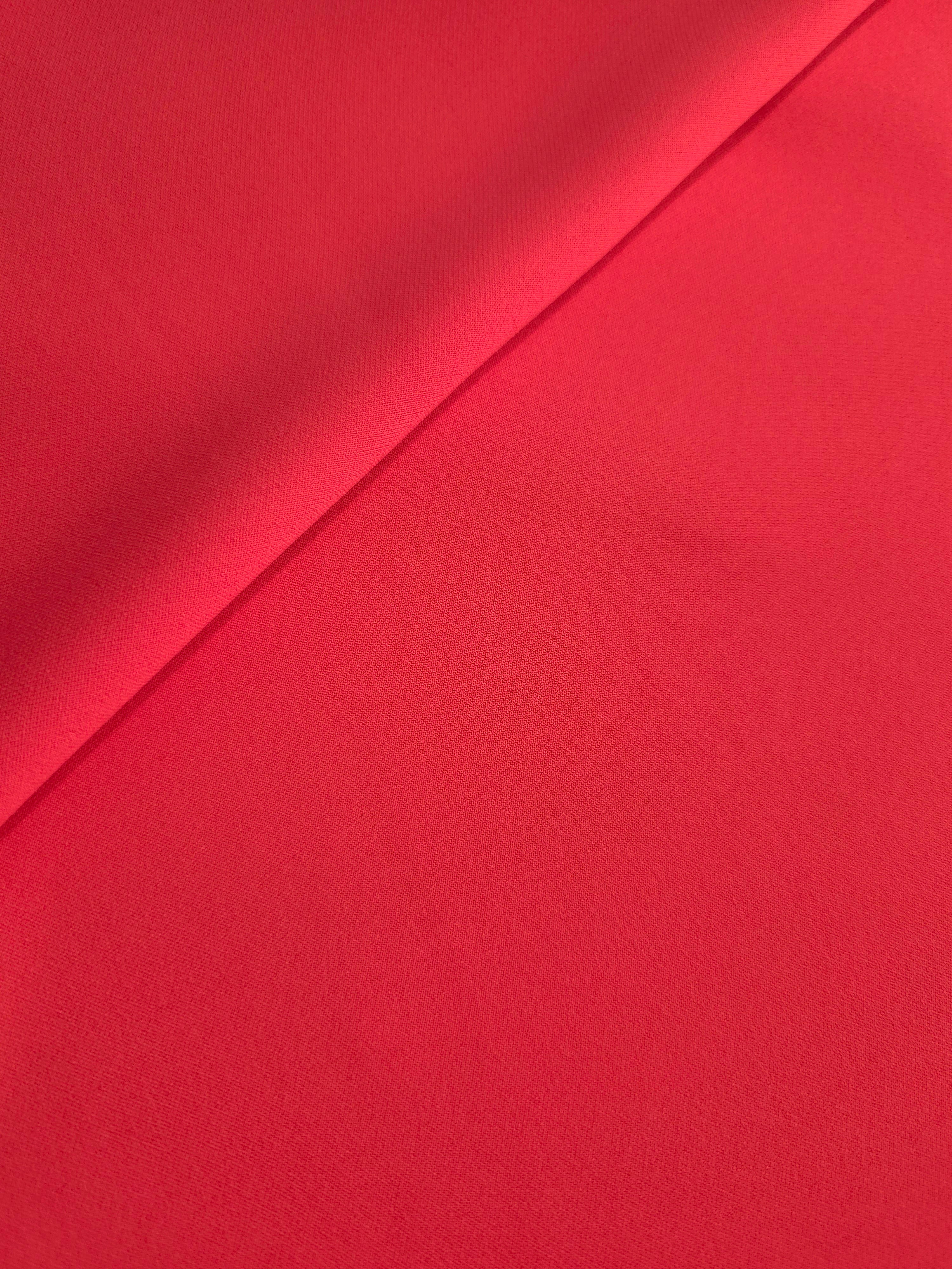 Loose fold of Crimson Red polyester crepe showing fluid drape for dresses, skirts and soft tailoring