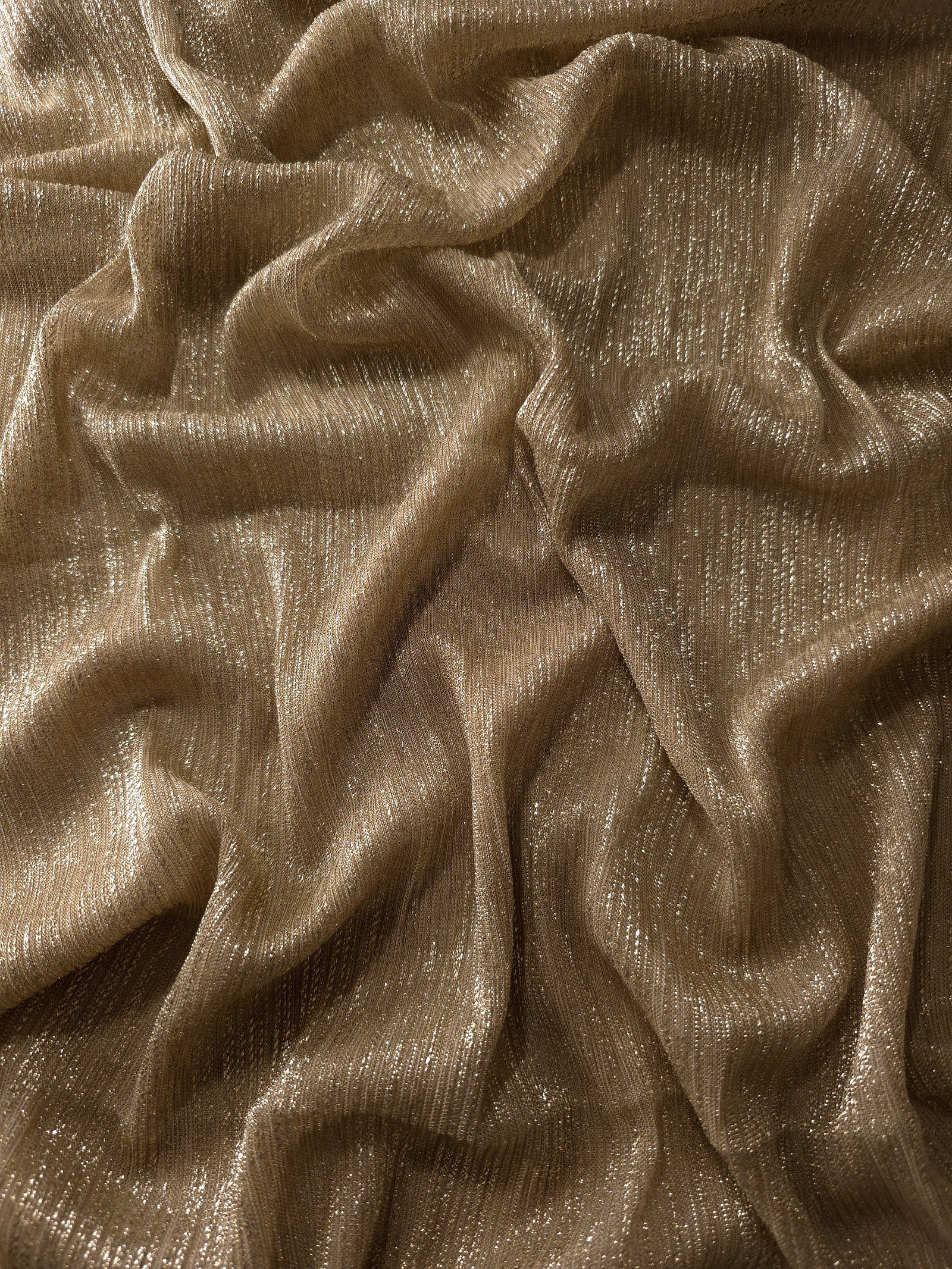 Draped Antique Taupe Gold Sheer Metallic Shimmer Stretch Tulle Fabric showing luminous reflective folds, soft transparency and flexible flow for dresses, dancewear, stagewear and occasion looks