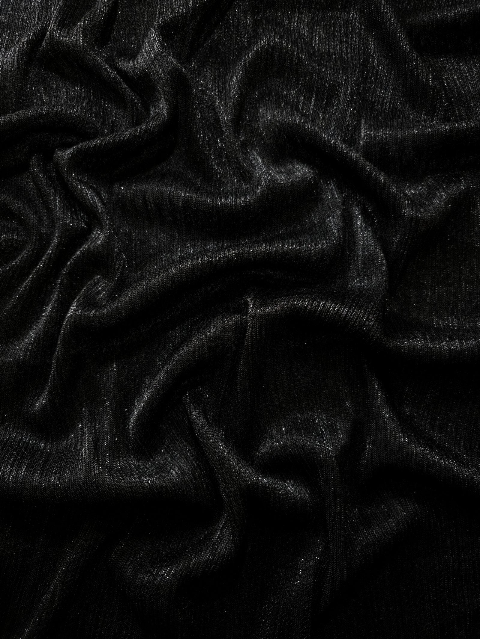 Draped Charcoal Black Sheer Metallic Shimmer Stretch Tulle Fabric showing luminous reflective folds, soft transparency and flexible flow for dresses, dancewear, stagewear and occasion looks