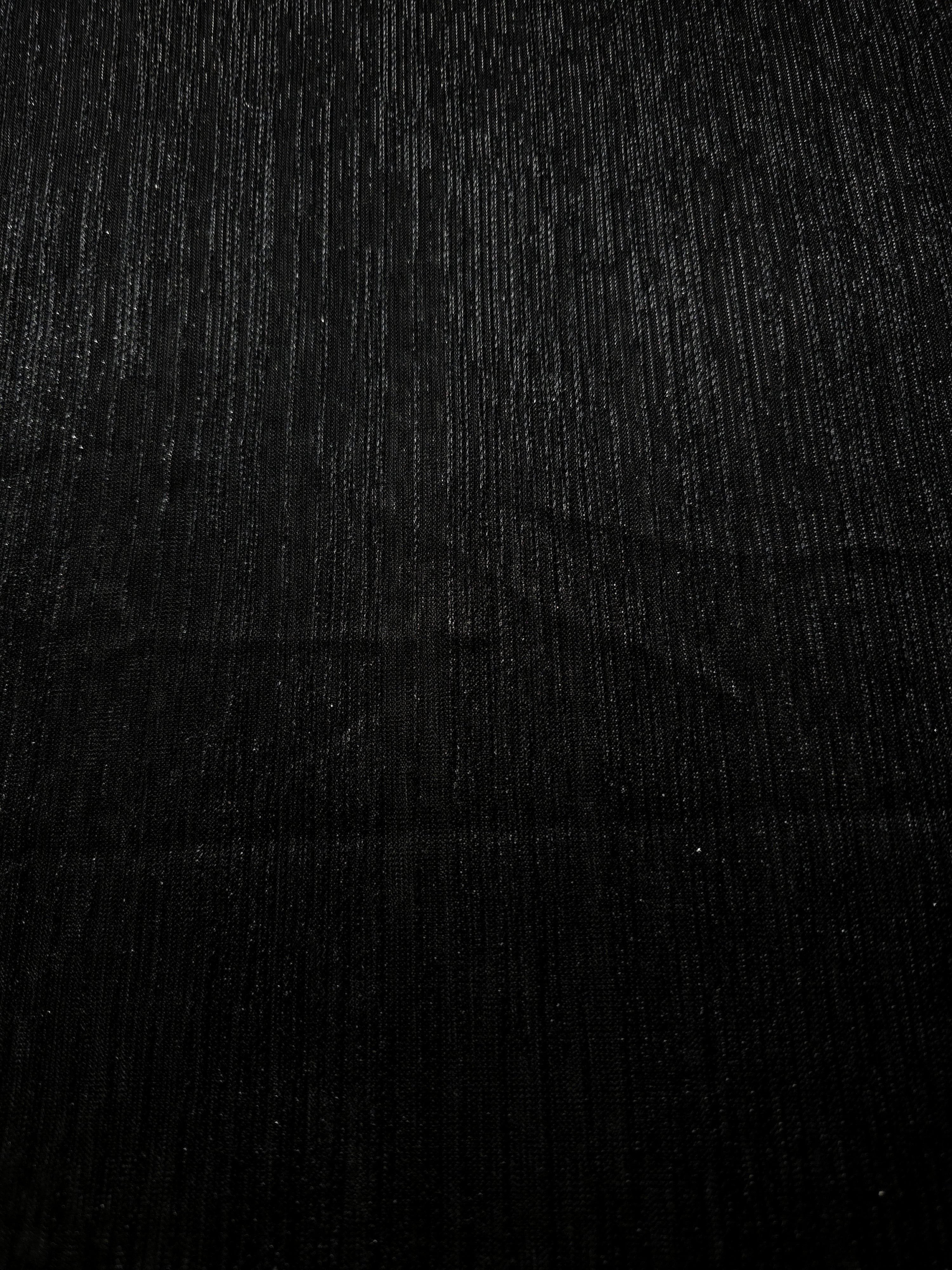 Surface view of Charcoal Black Sheer Metallic Shimmer Stretch Tulle Fabric showing even metallic shimmer, fine sheer tulle texture, translucent finish and stretch for overlays, dresses and performance wear