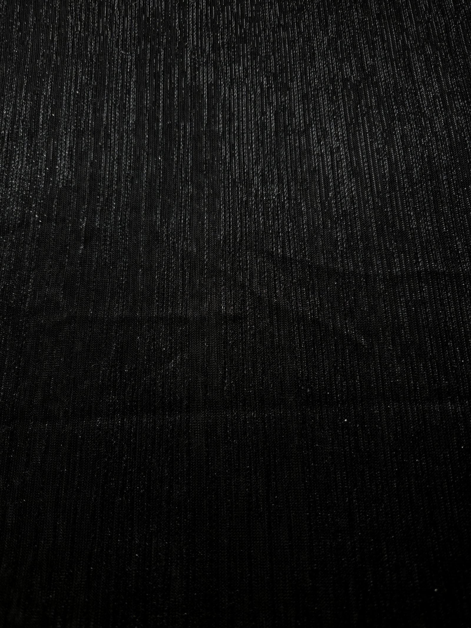 Surface view of Charcoal Black Sheer Metallic Shimmer Stretch Tulle Fabric showing even metallic shimmer, fine sheer tulle texture, translucent finish and stretch for overlays, dresses and performance wear