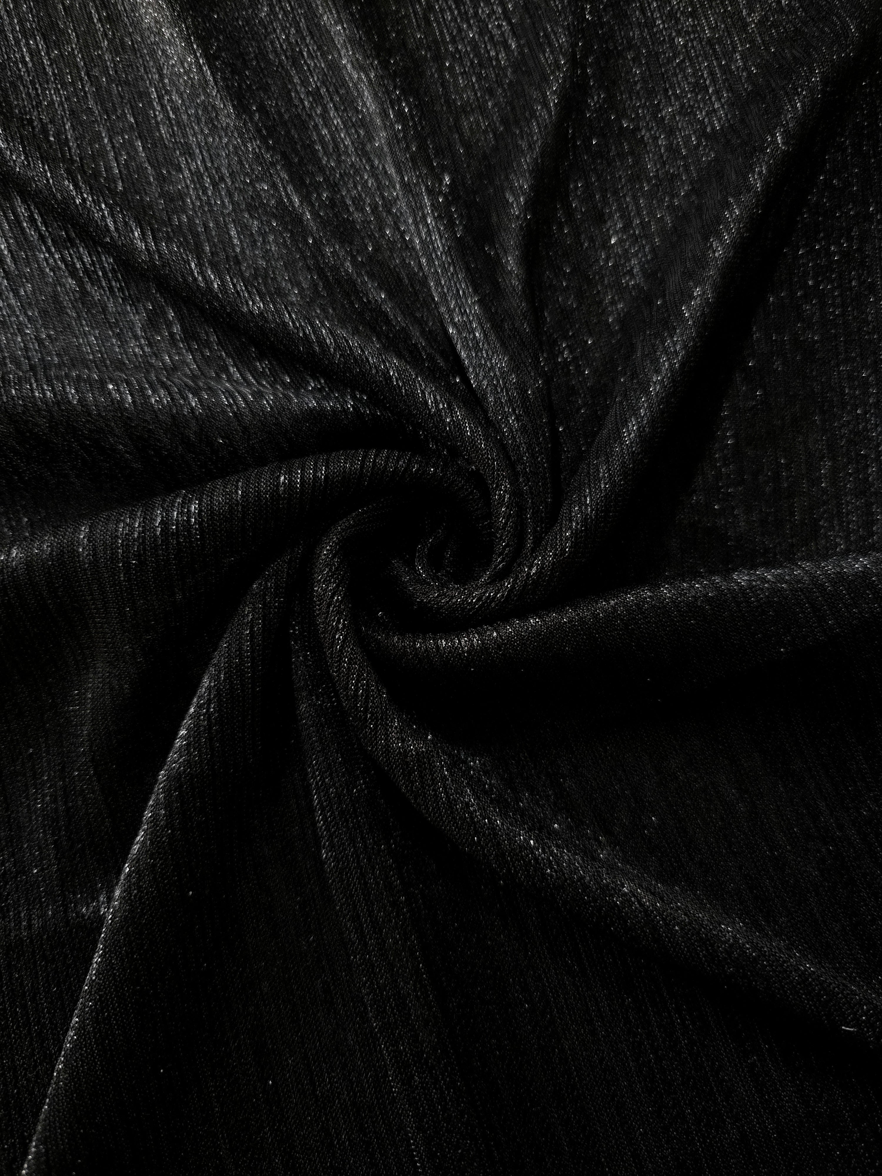 Swirl-draped Charcoal Black Sheer Metallic Shimmer Stretch Tulle Fabric showing fluid movement, reflective shimmer, airy transparency and flexible stretch for dresses, dancewear and stage looks