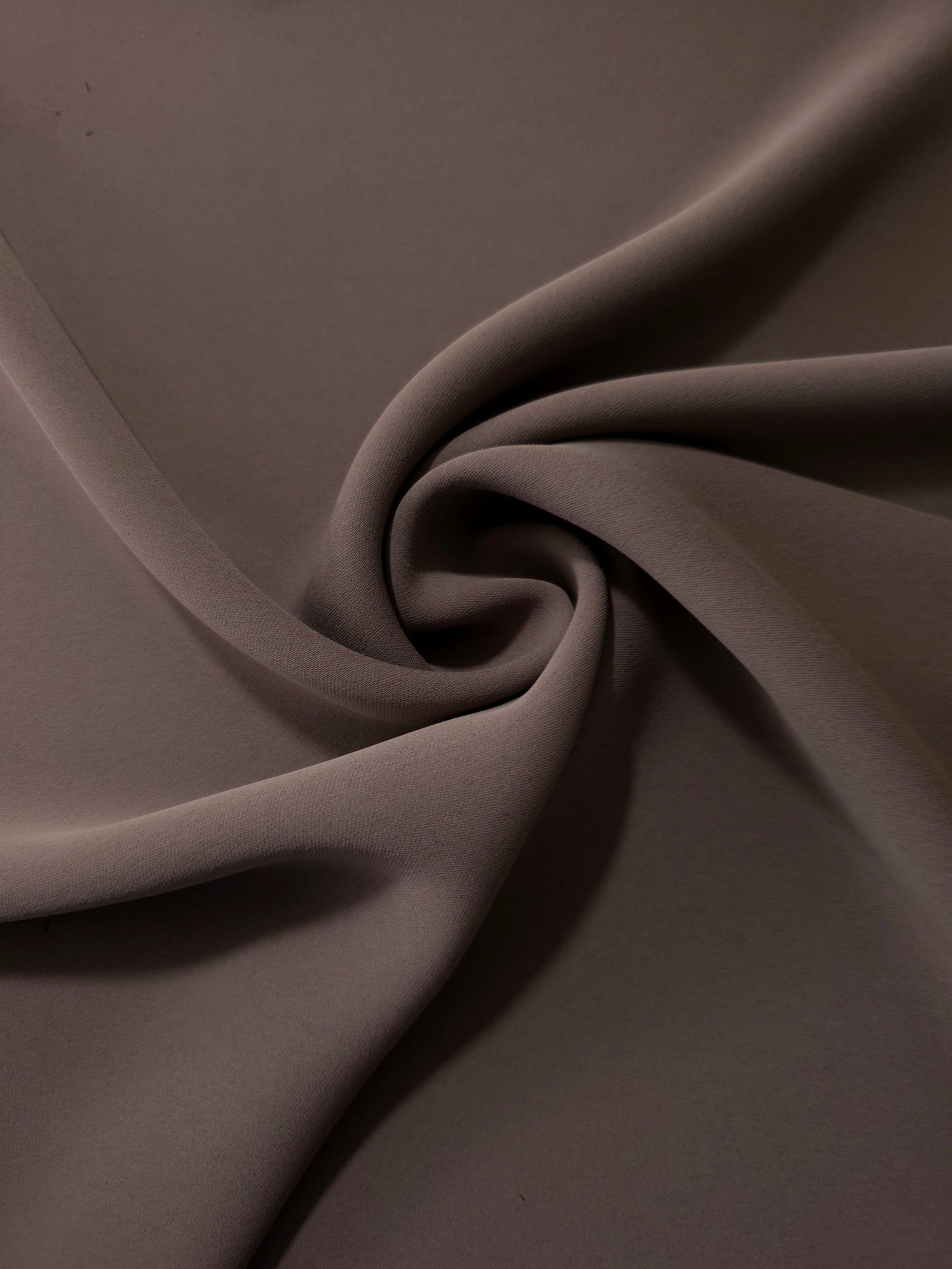 Circular drape of Dark Cocoa Taupe polyester crepe showing flowing movement for occasion dresses and modest fashion