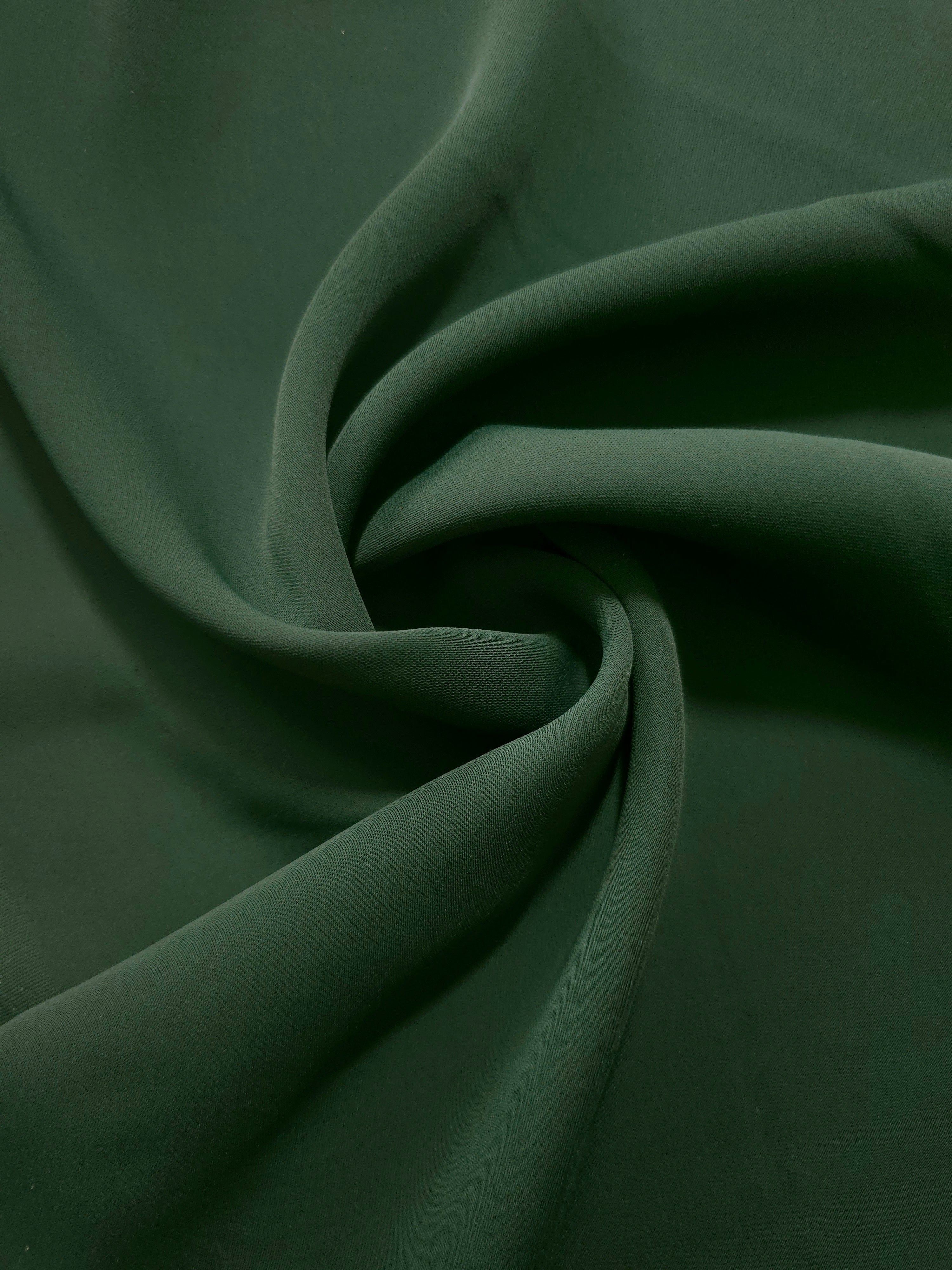 Dark Hunter Green polyester crepe in a spiral drape, showing flowing form for dresses and modest garments