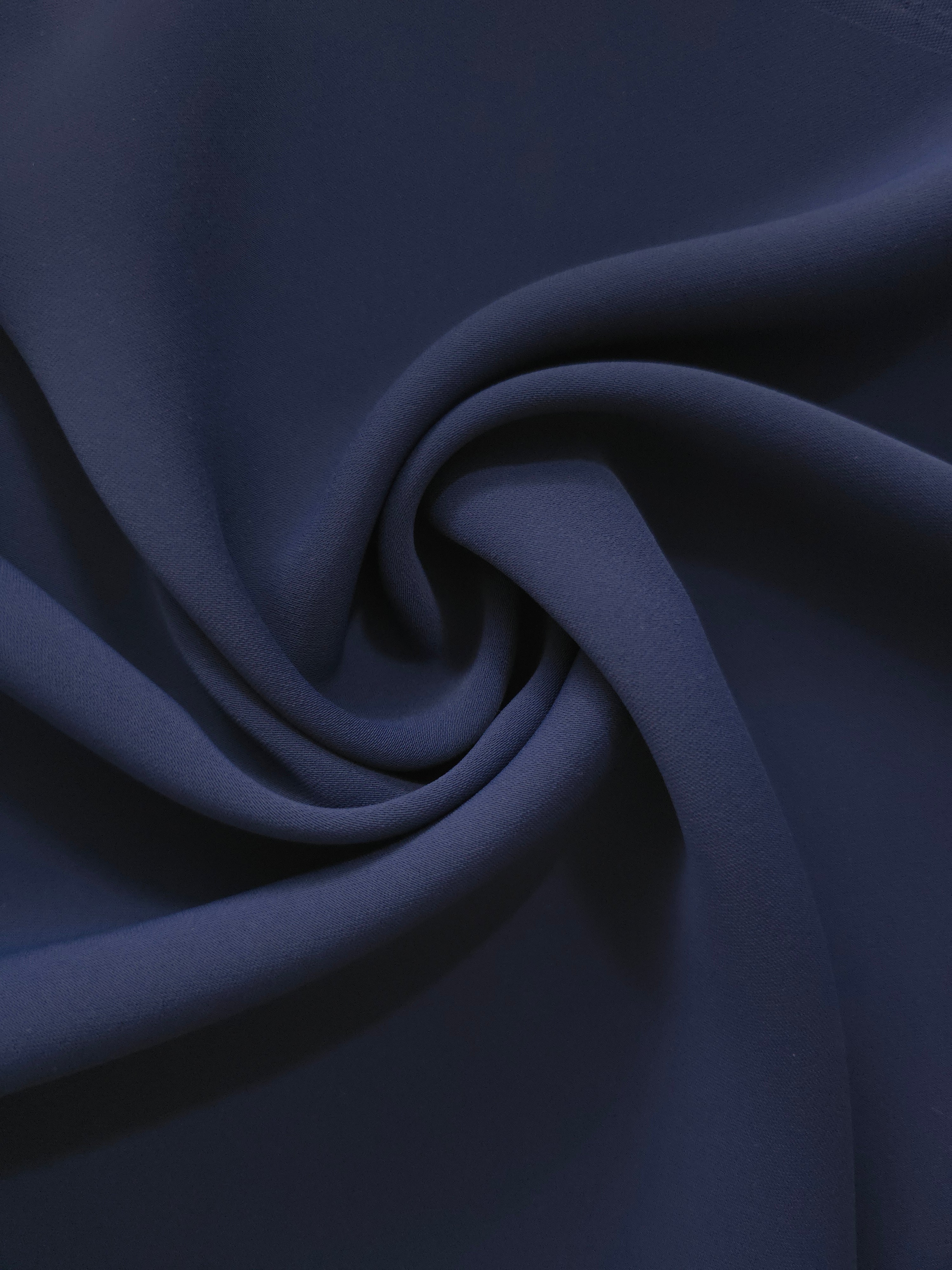 Dark Navy Blue Italian-style polyester crepe in a circular swirl, highlighting supple drape for garment making