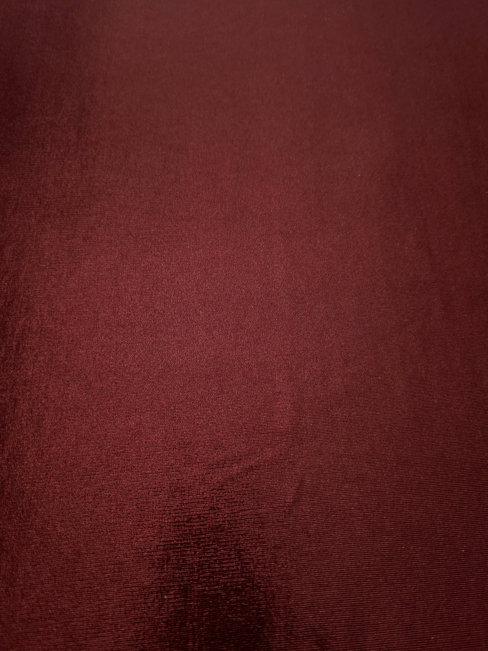 Full surface of Deep Burgundy metallic stretch fabric, highlighting luminous foil sheen for stage costumes, dresses and fashion design