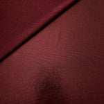 Gently folded Deep Burgundy shimmer spandex fabric showing luminous foil finish for tops, skirts and occasion garments