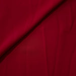 Soft fold of Deep Cherry Red opaque polyester crepe showing fluid dressmaking drape for dresses and skirts