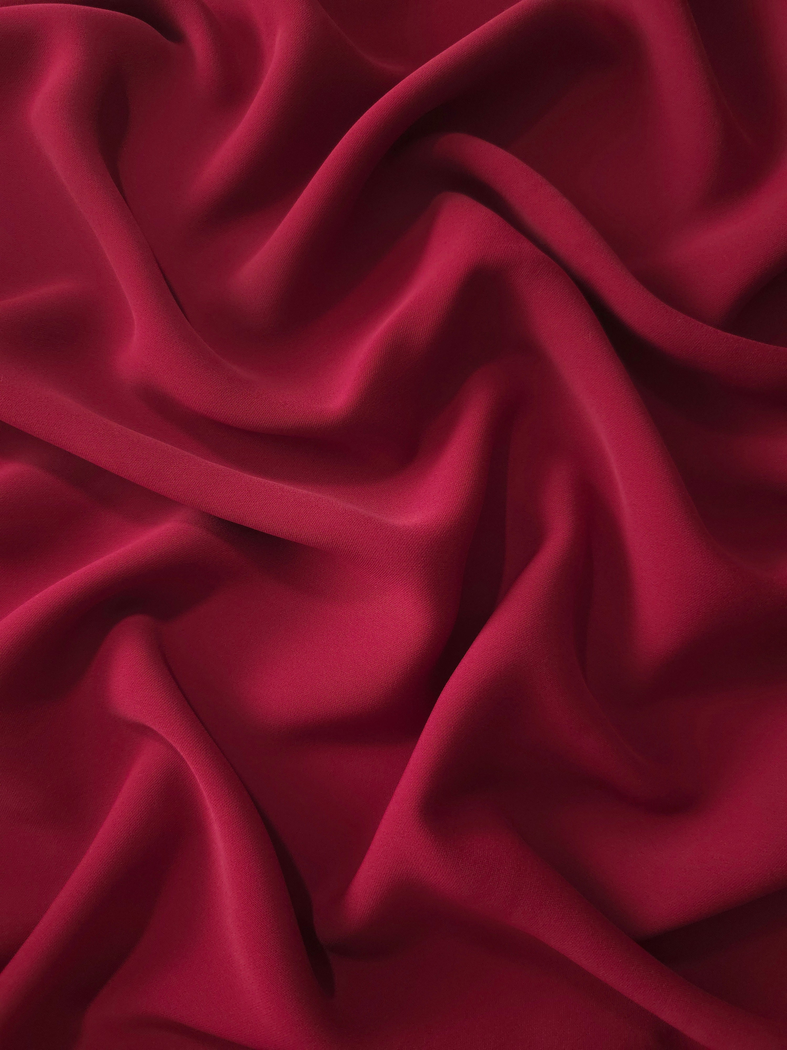 Long draped folds of Deep Cranberry Red polyester crepe showing flowing coverage for dresses and modest wear