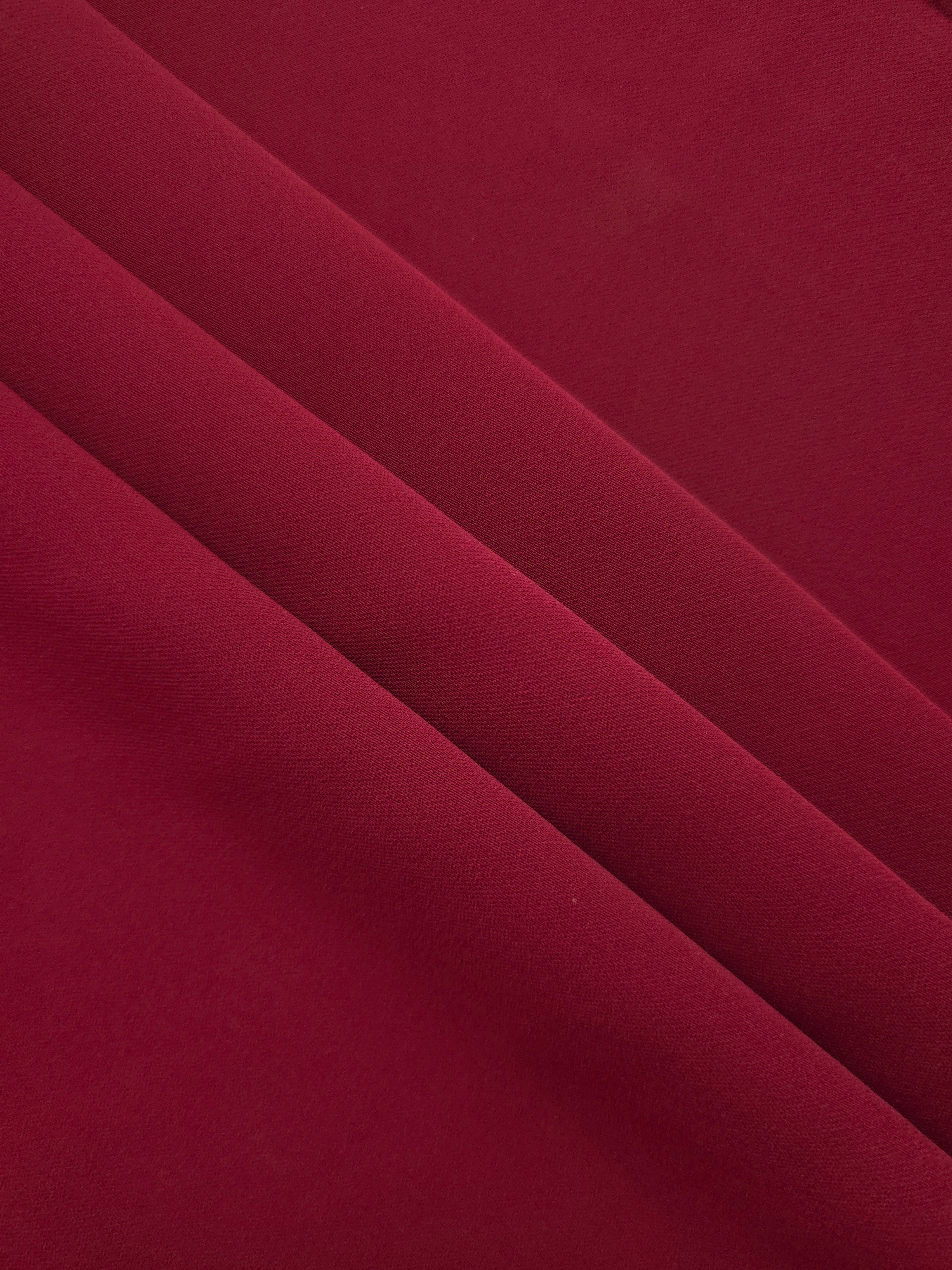 Layered Deep Cranberry Red polyester crepe showing soft body and gentle mechanical stretch for dressmaking