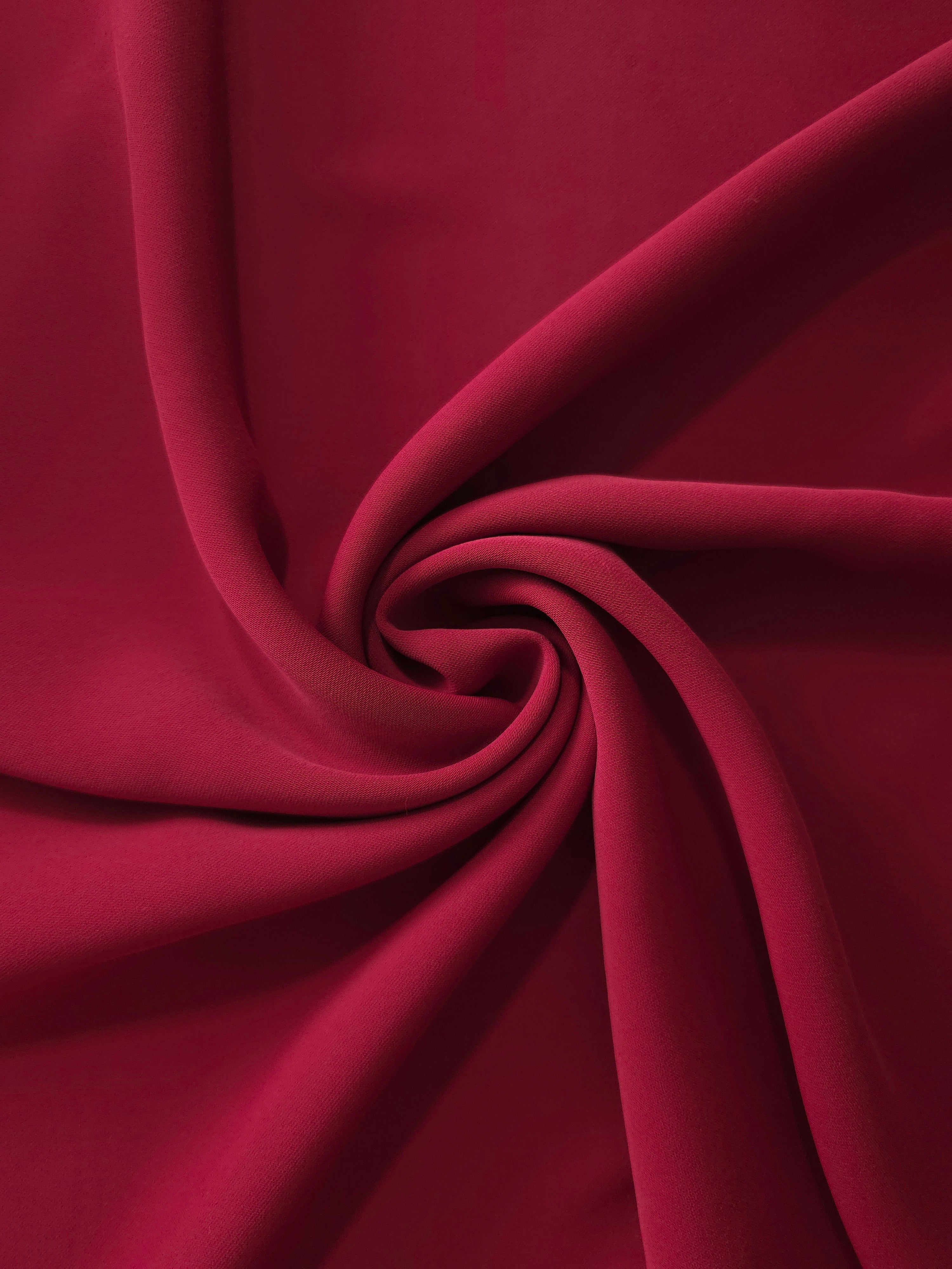 Circular drape of Deep Cranberry Red polyester crepe showing flowing movement for occasion dresses and modest fashion