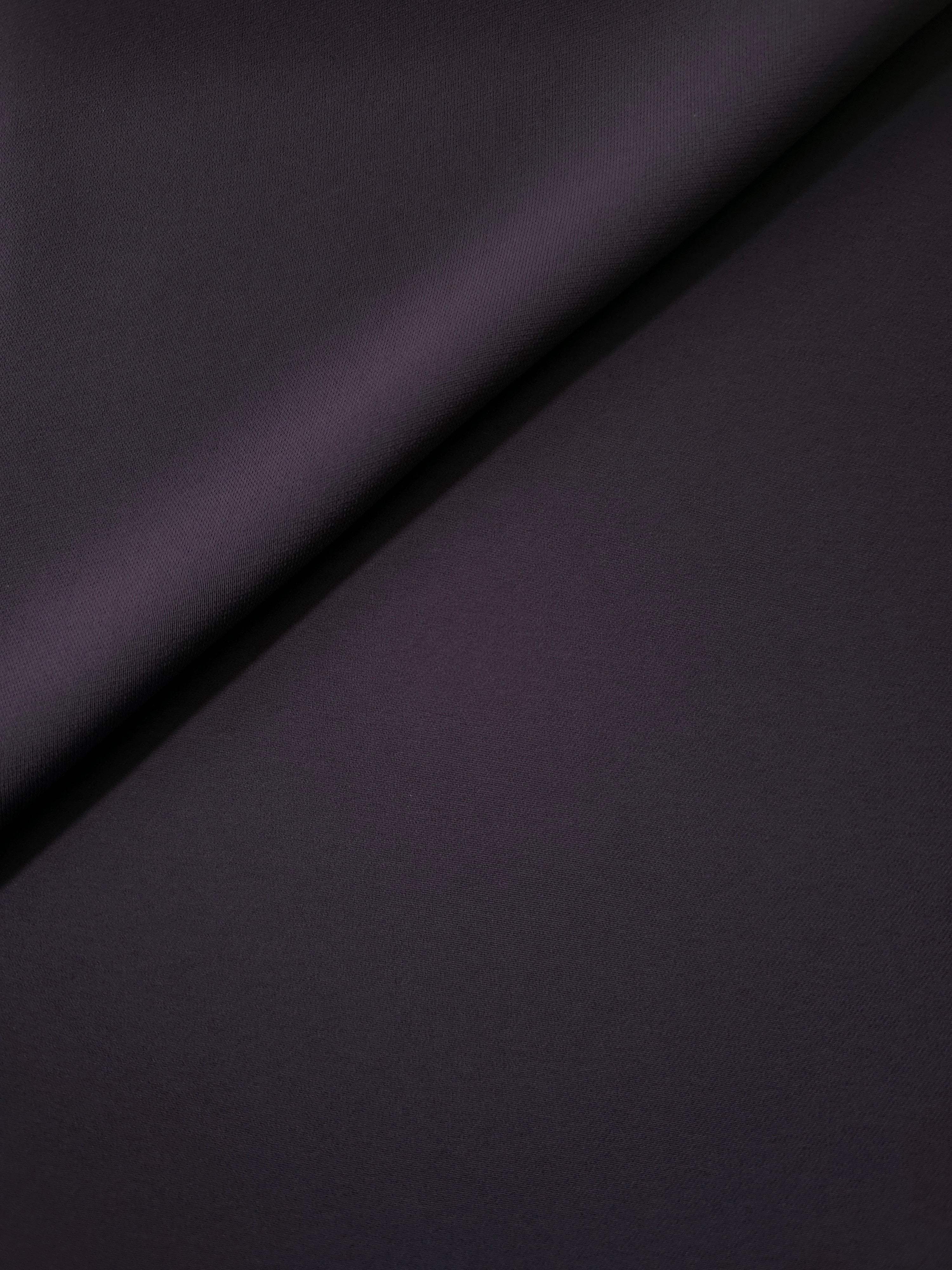 Loose fold of Deep Eggplant Purple polyester crepe showing smooth fluid drape for dresses, skirts and soft tailoring