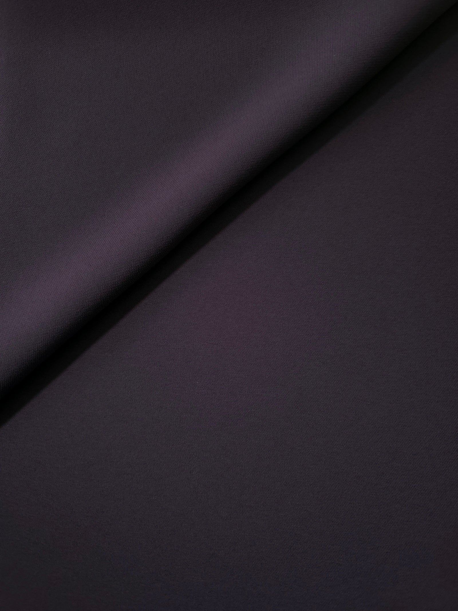 Loose fold of Deep Eggplant Purple polyester crepe showing smooth fluid drape for dresses, skirts and soft tailoring