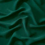 Draped folds of Deep Emerald Green polyester crepe showing opaque coverage and fluid movement for garment making