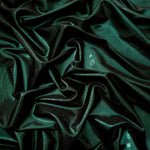 Deep Emerald Green shimmer stretch fabric in draped folds, highlighting metallic foil sheen for evening dresses, costumes and statement apparel